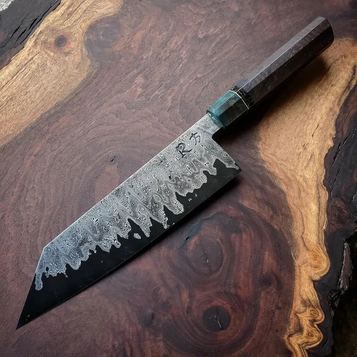 A collaboration with my friend Justin (Runningman Forge) 7” bunka of random damascus and  Hitachi Blue #2 Sanmai. Walnut and Maple burl octagonal handle with truestone spacer (2024)