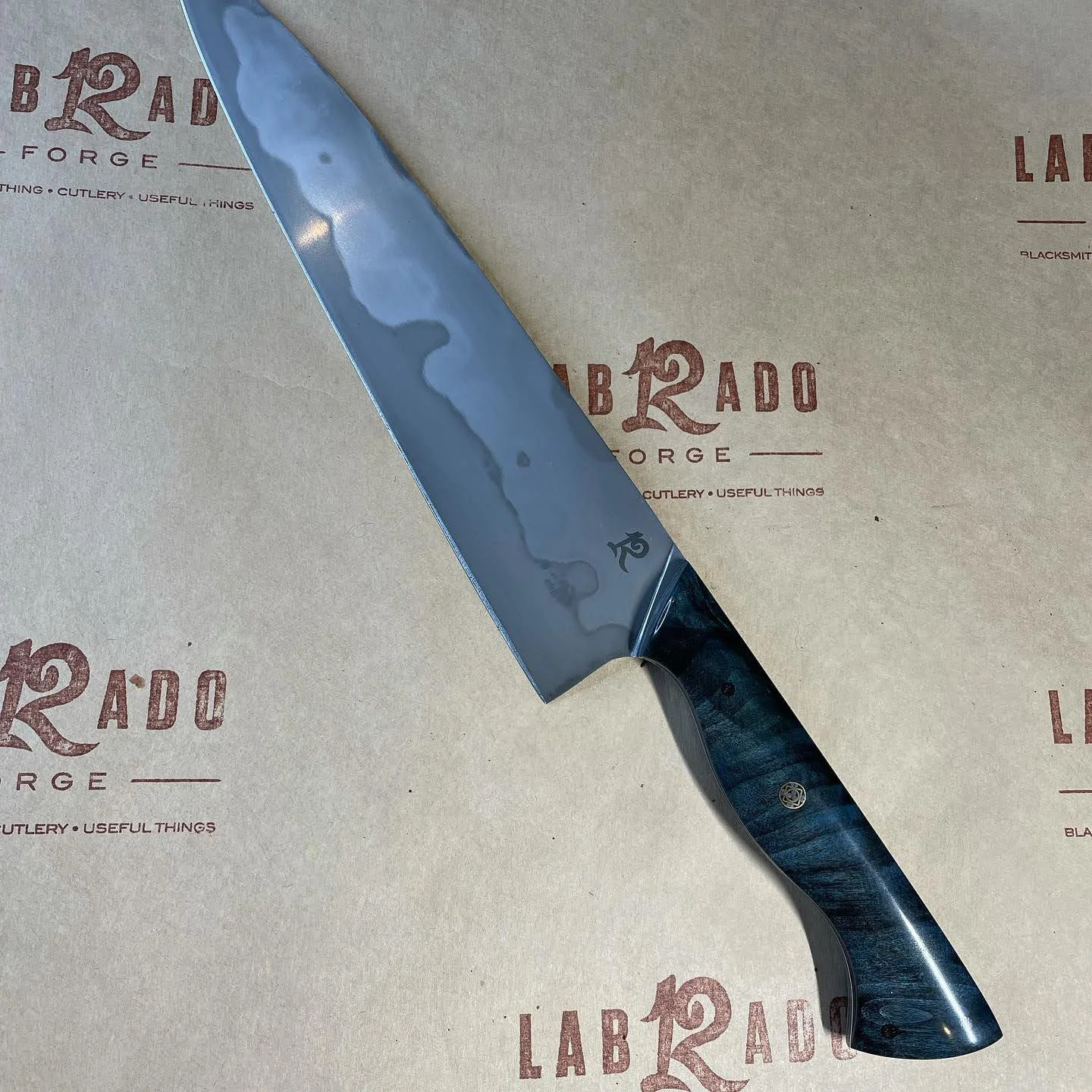 9” chef  of differentially heat treated 1095. Handle is dyed and stabilized sycamore (2023)