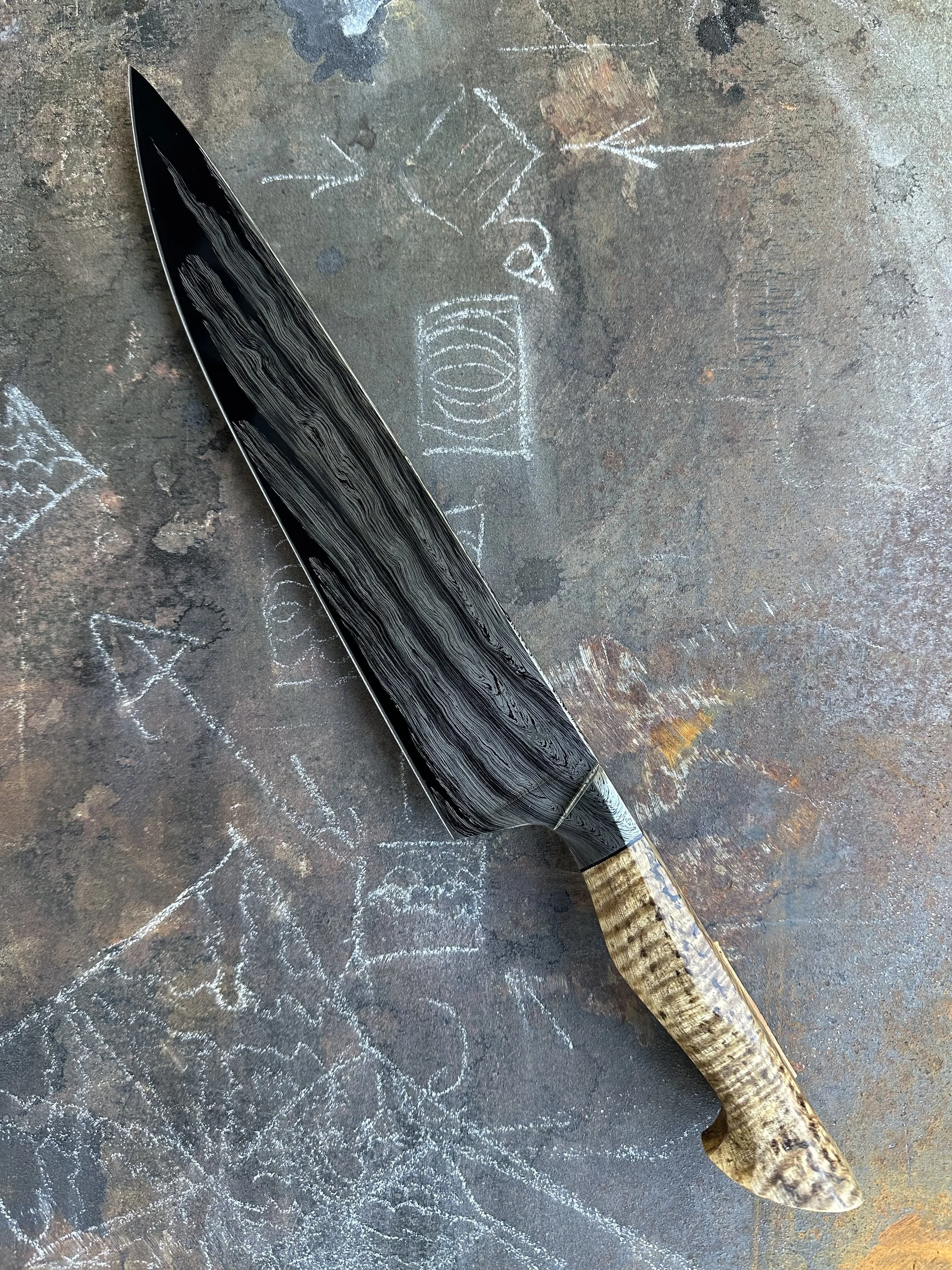 My first integral knife 10 inch chef.
“Wariha Tetsu” damascus pattern of 1084 and 15n20. “Japanese Cowboy” handle of spalted curly maple with black spacer. The Wariha testsu pattern and the Japanese cowboy handle were both taught to me by Mareko Maum