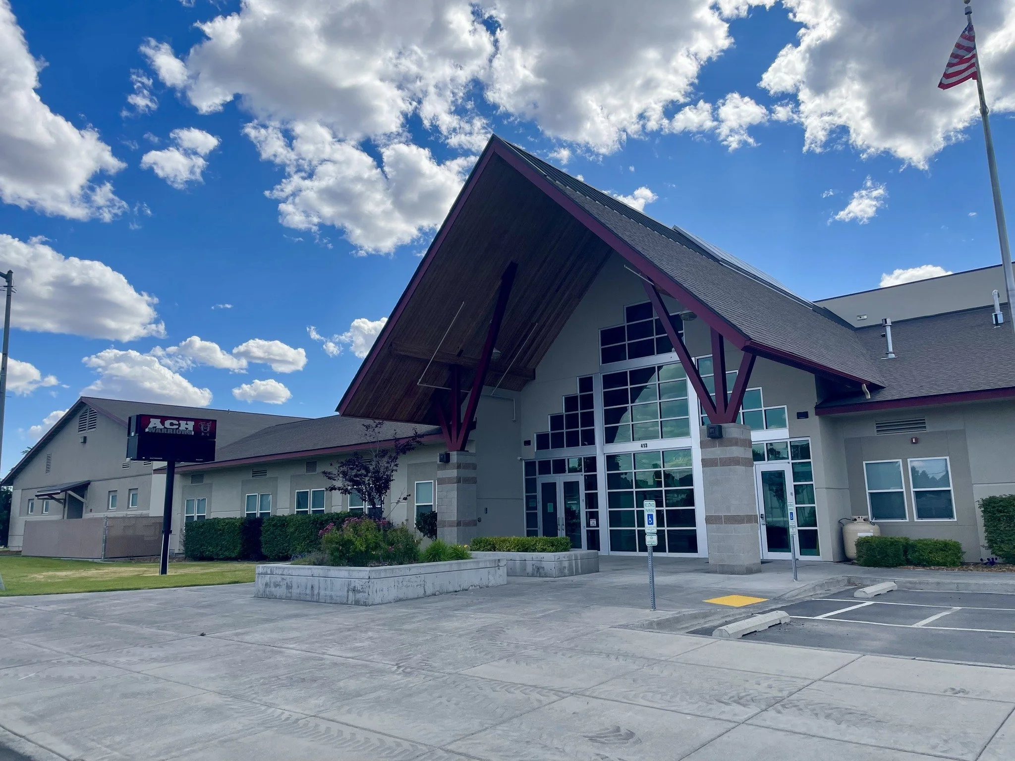 Photo of the main entrance of ACH High School in Coulee City, Washington. The afternoon sky is bright blue with the occasional puffy white clouds.