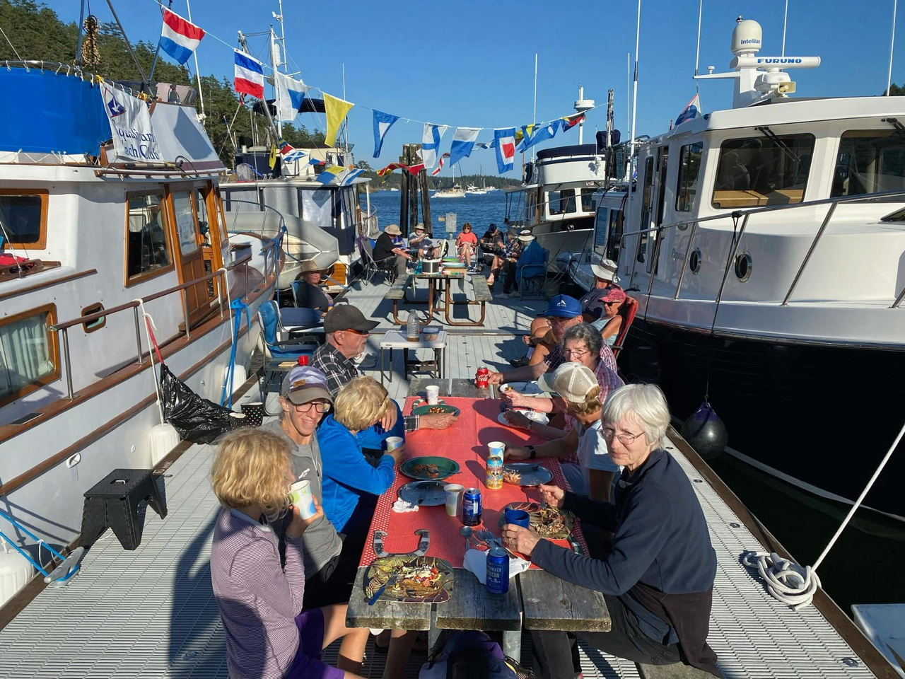 Squalicum Yacht Club members gather on the dock at Stuart Island, eating, drinking, and talking
