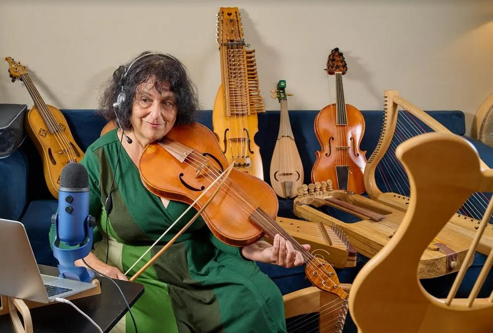 Shira surrounded by medieval string instruments in the recording studio