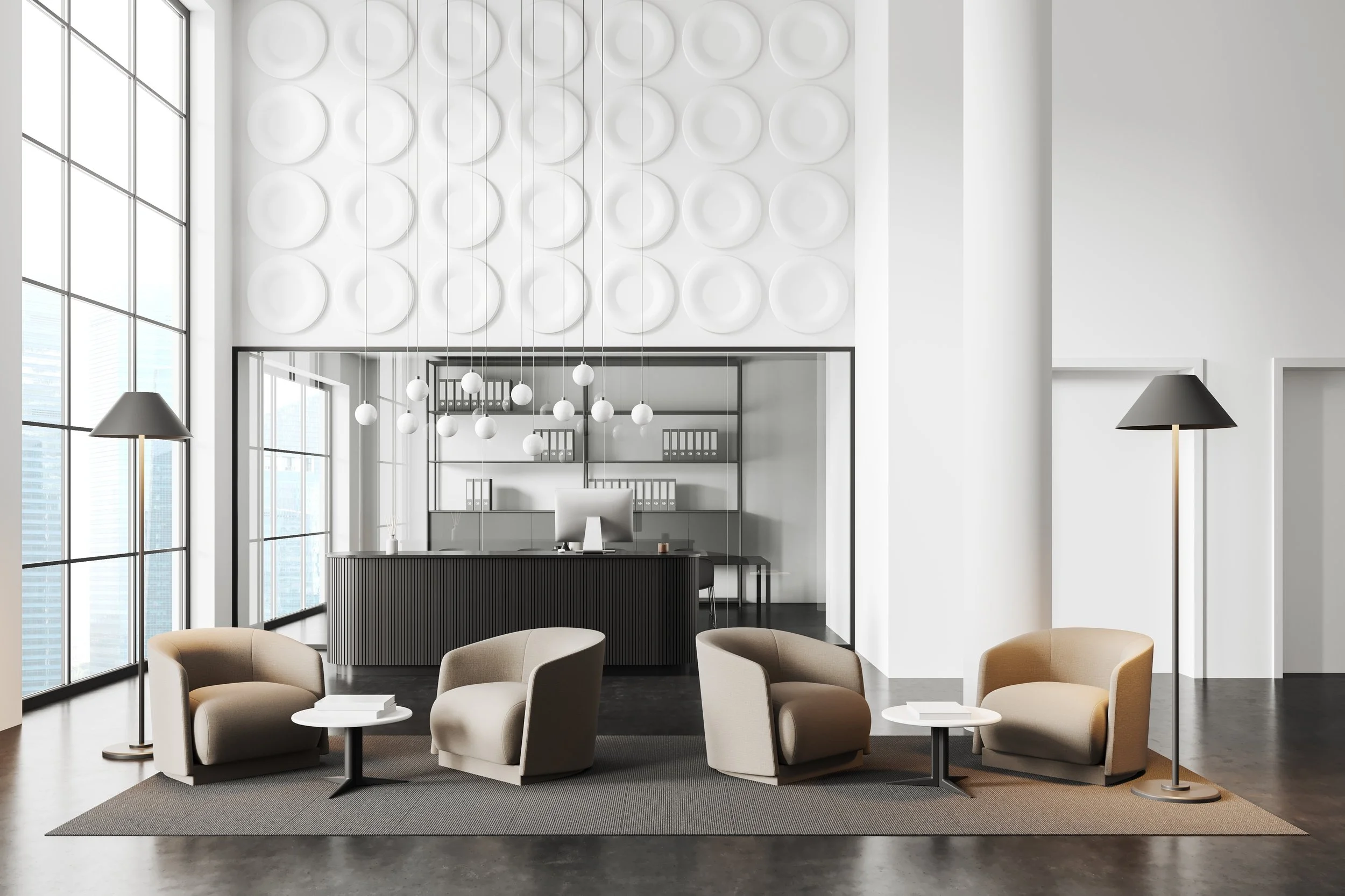 Modern office reception area with beige chairs, small white tables, black floor lamps, a reception desk with computer, behind which is a glass wall and shelves with binders, large windows letting in natural light, minimalist white walls, and decorati