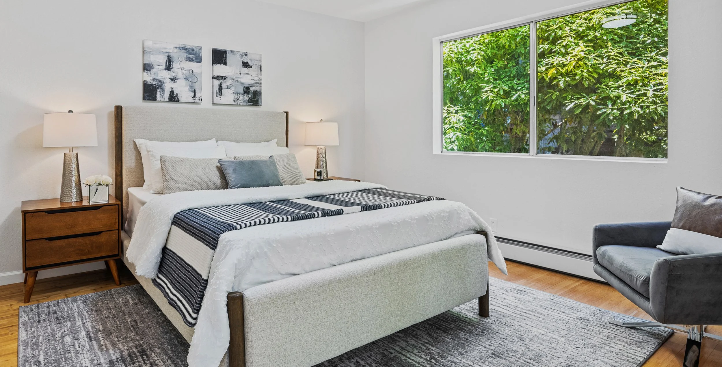 Minimal staged bedroom with large window and tree views in renovated San Francisco home