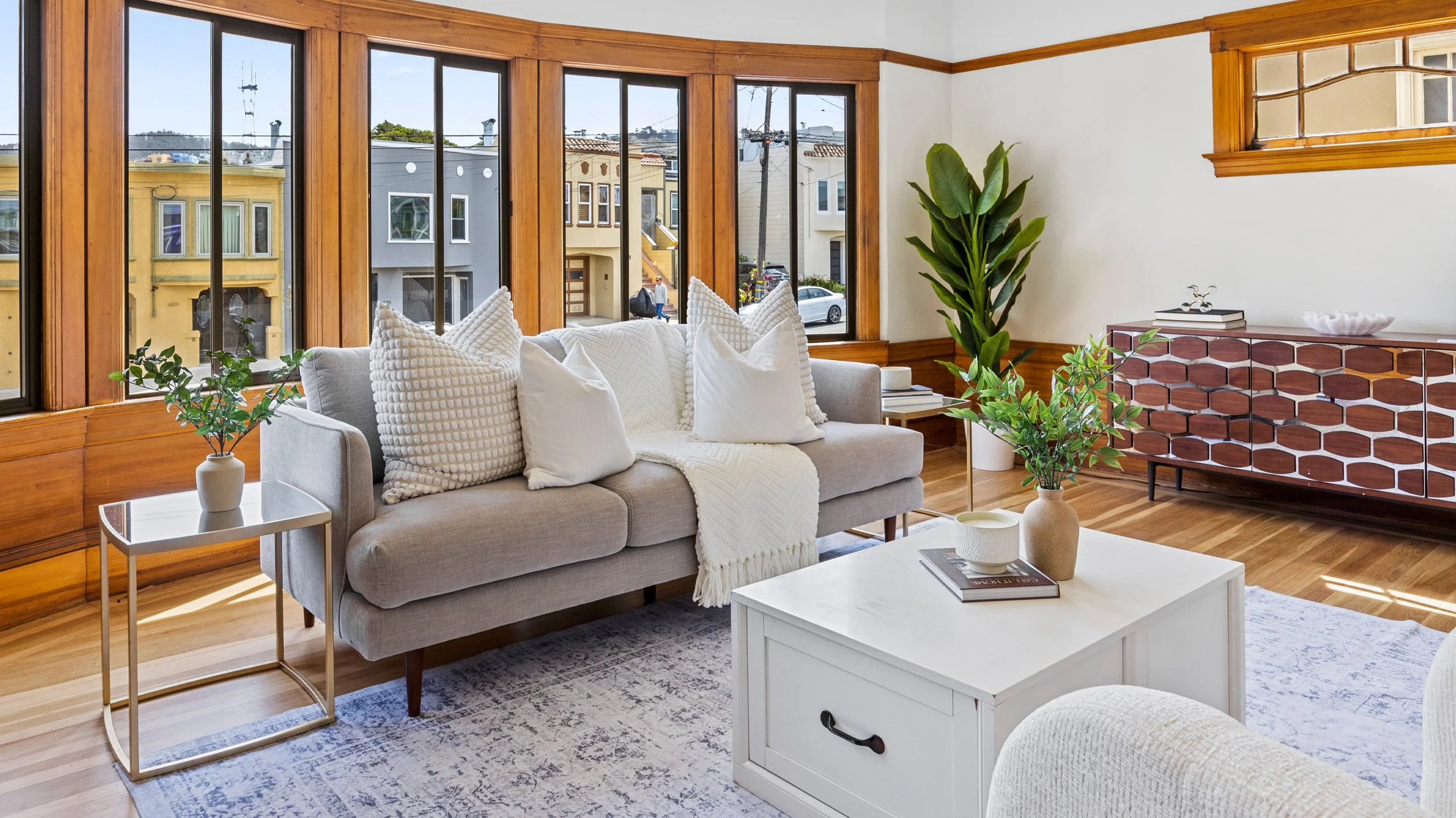 Staged living room with large bay windows in renovated San Francisco home prepared for market