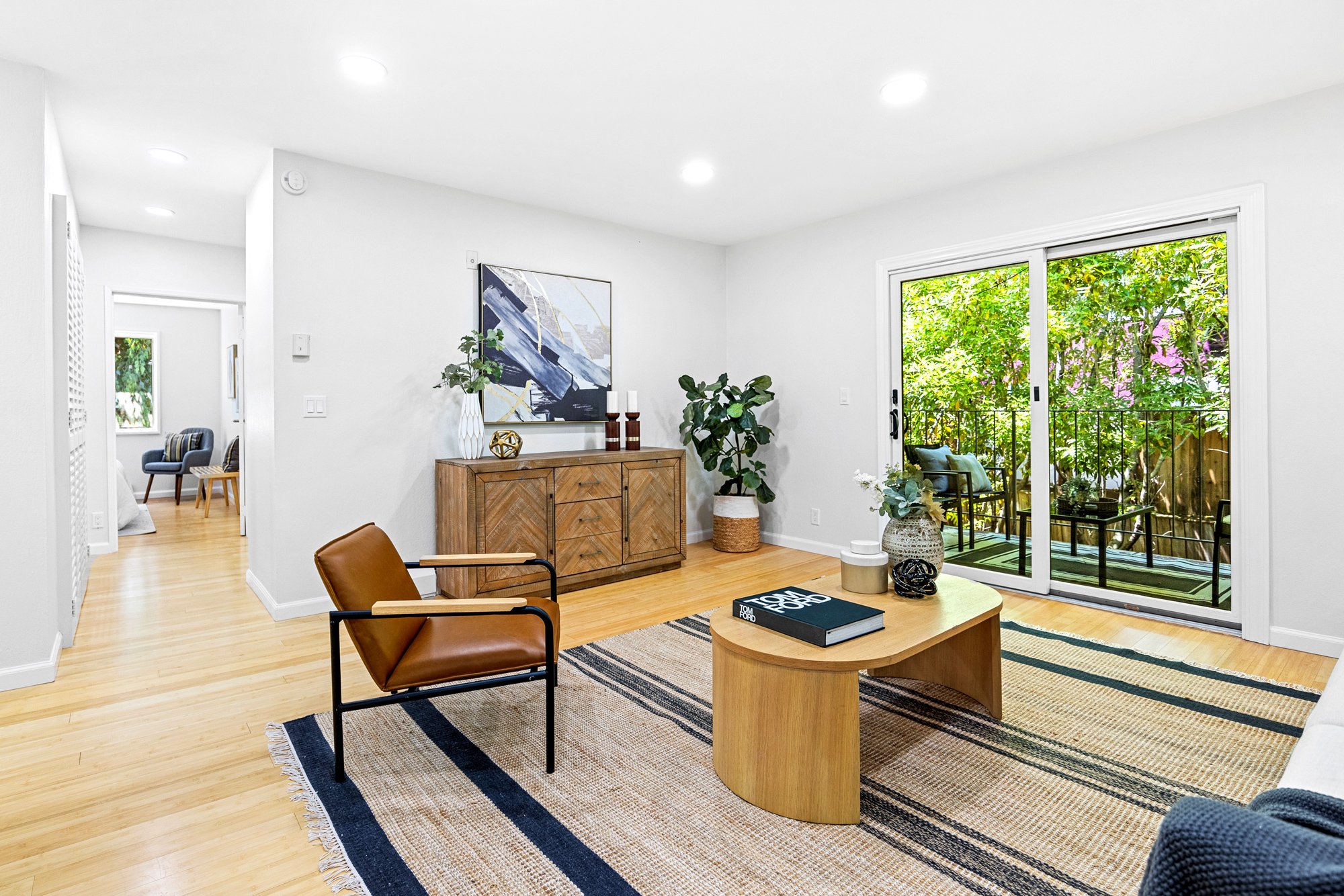Bright sitting area with sofa, wood paneling, large windows, and modern staging decor