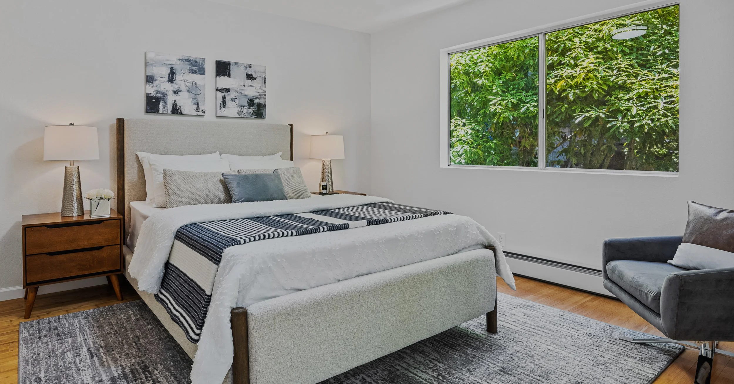 Minimal staged bedroom with large window and tree views in renovated San Francisco home