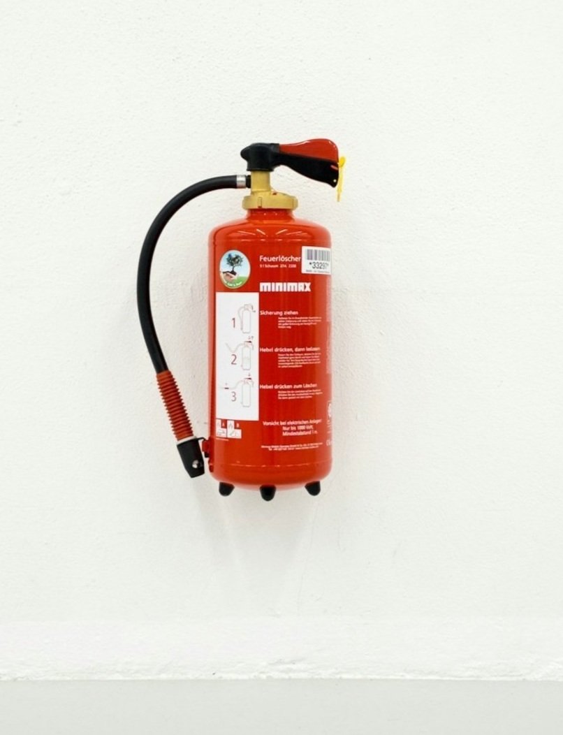 Red fire extinguisher mounted on a white wall.