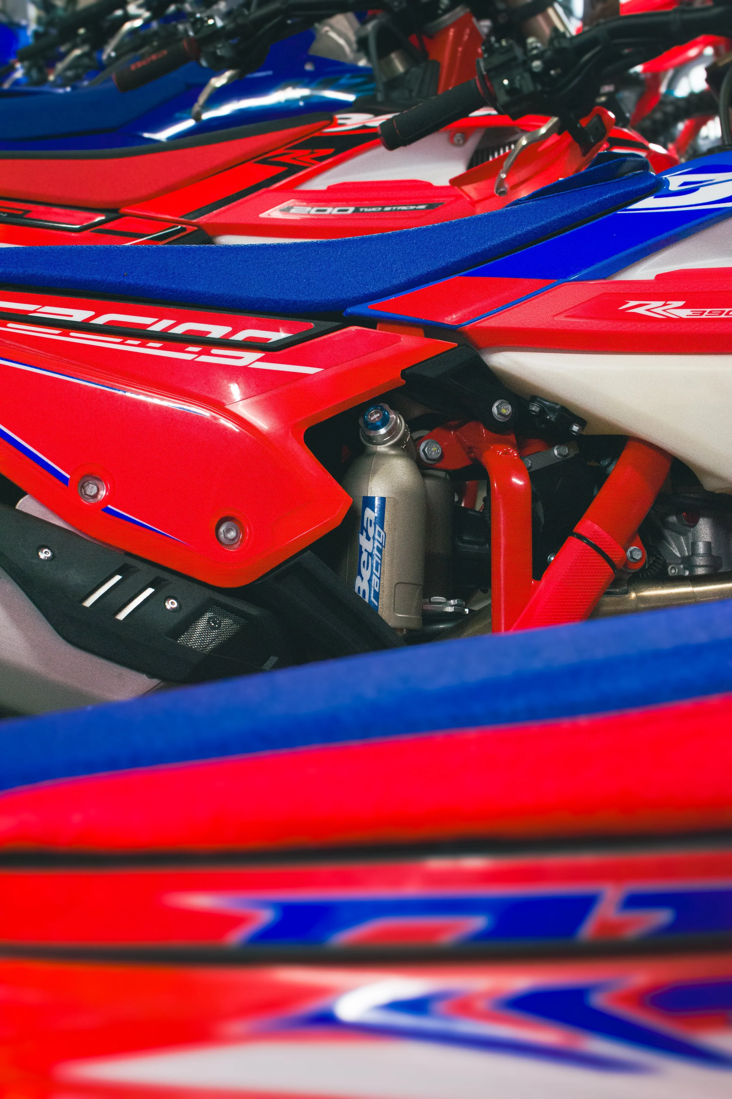 Close-up of a red, blue, and white motocross bike with visible suspension components and graphic decals.