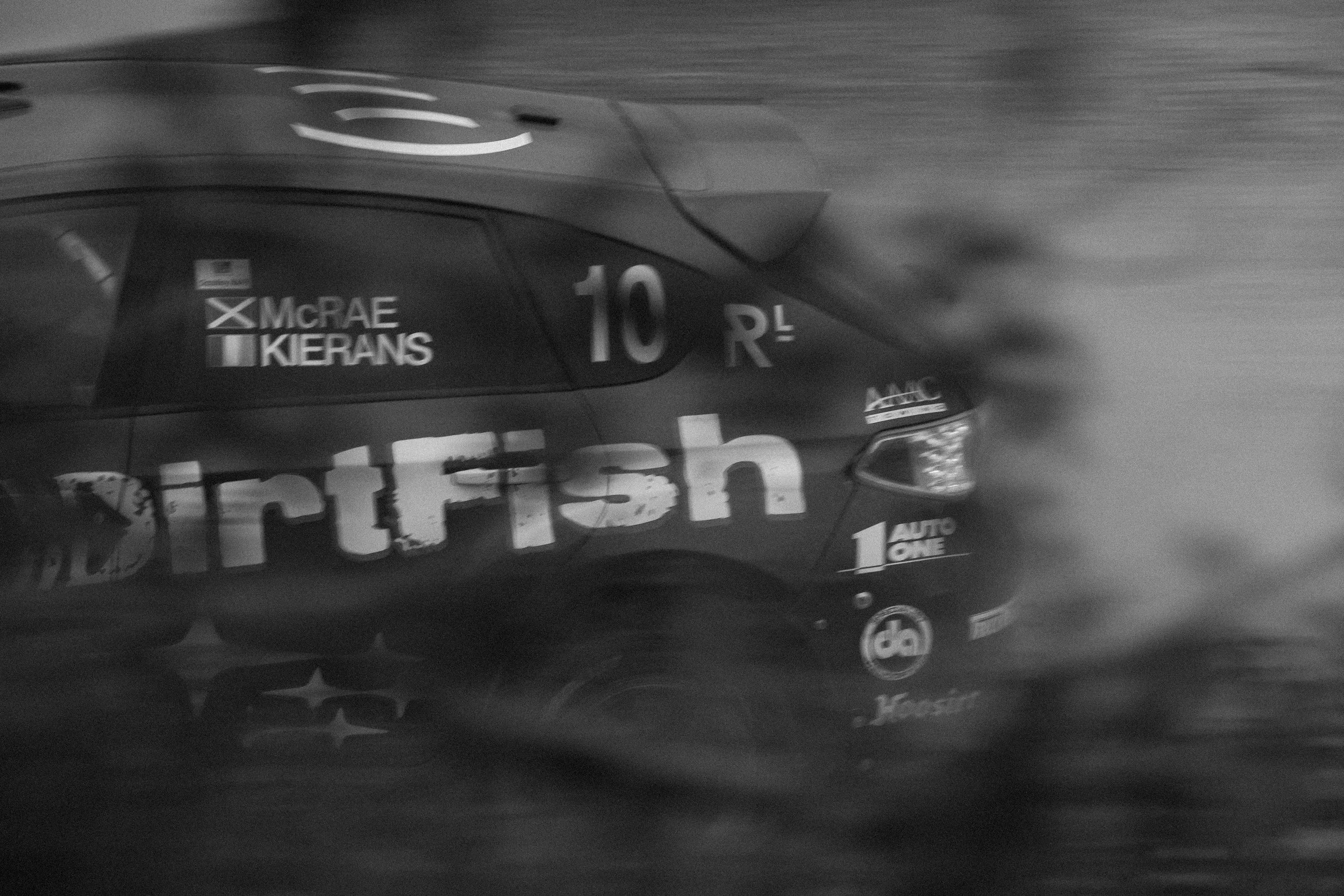 Black and white image of a race car with the number 10, sponsors' logos, and driver names Macrae and Kierans.