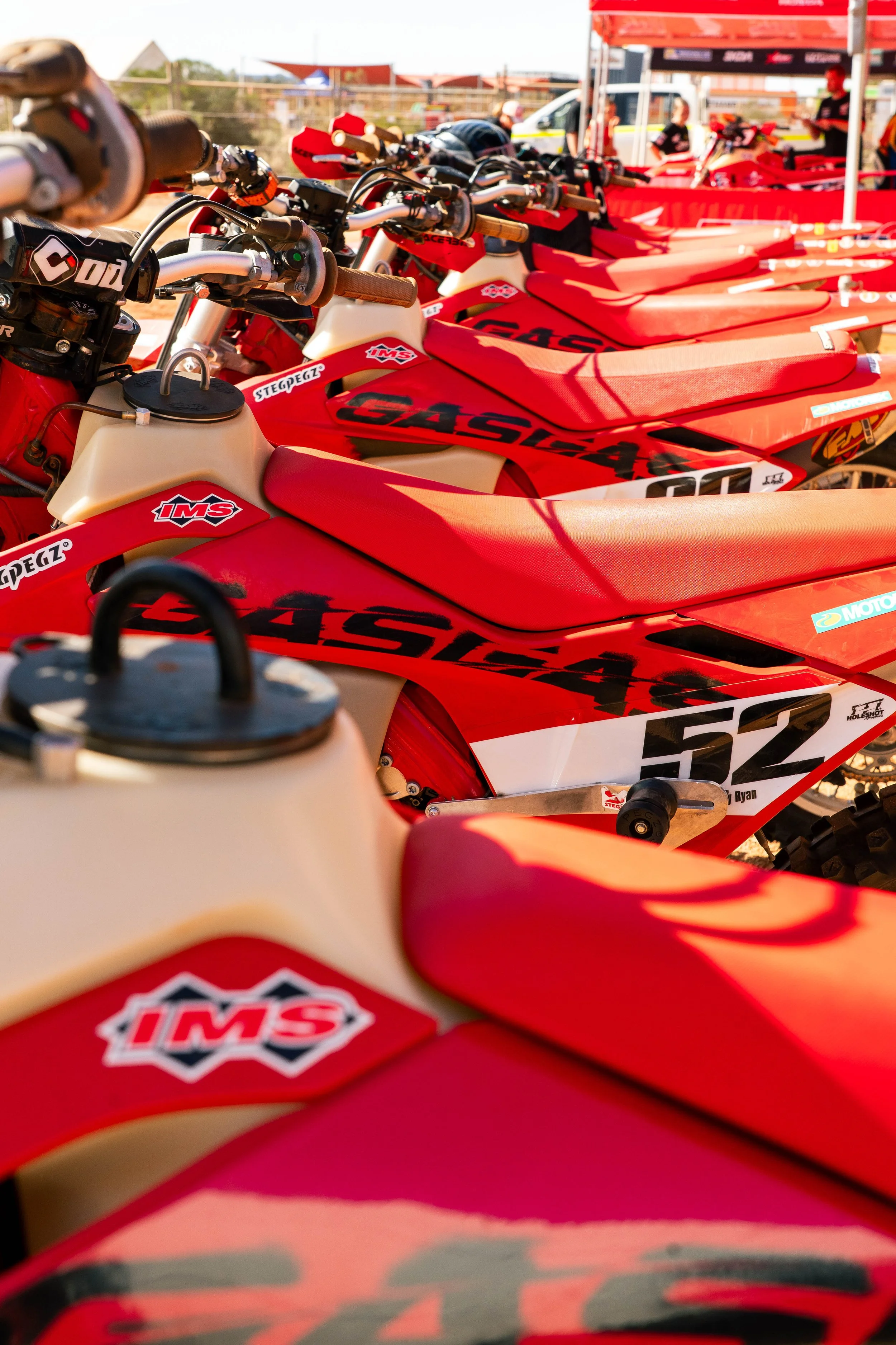 A lineup of red and white motocross bikes with black and red decals parked at a racing event