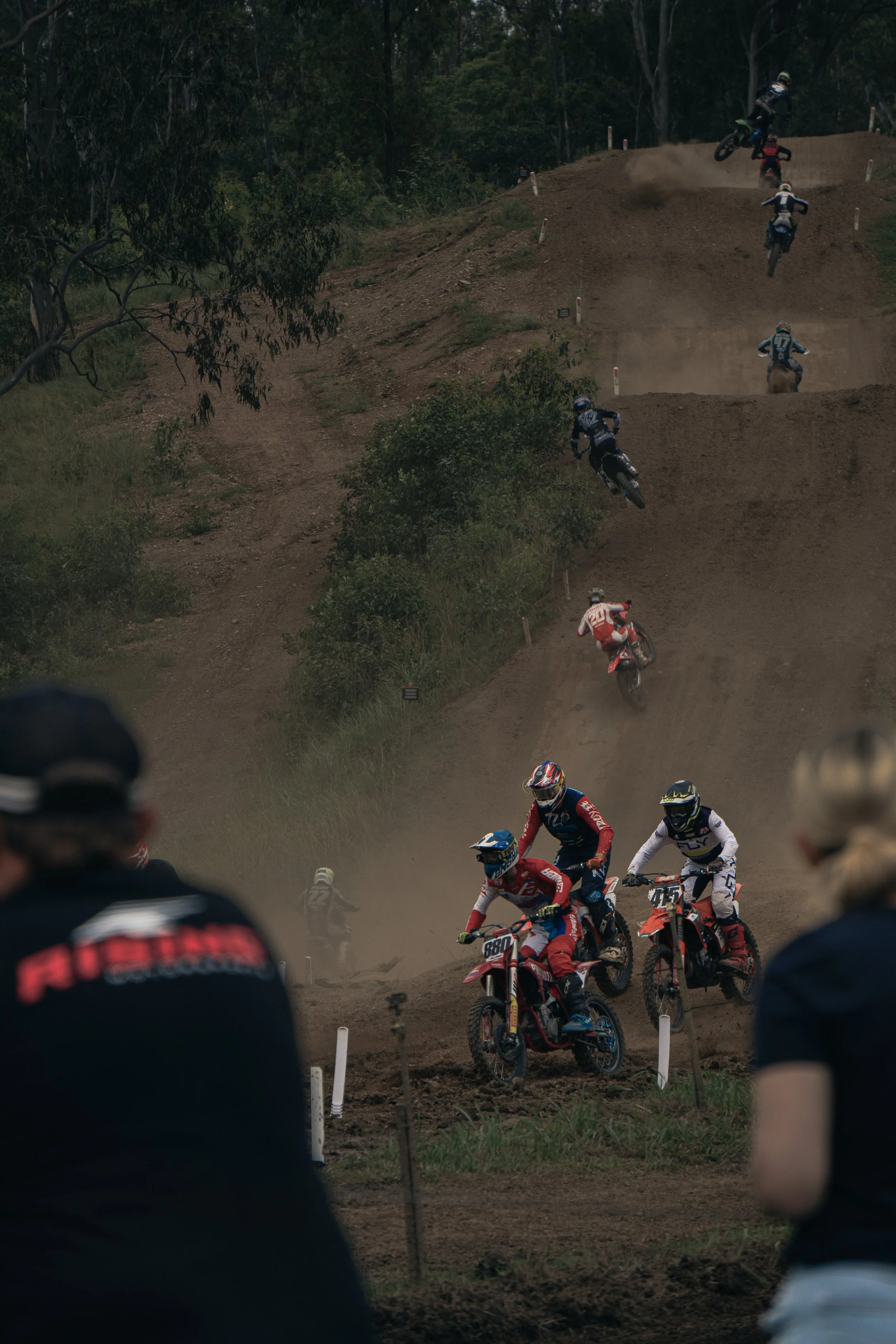 Motocross race on a dirt track with riders jumping and racing.