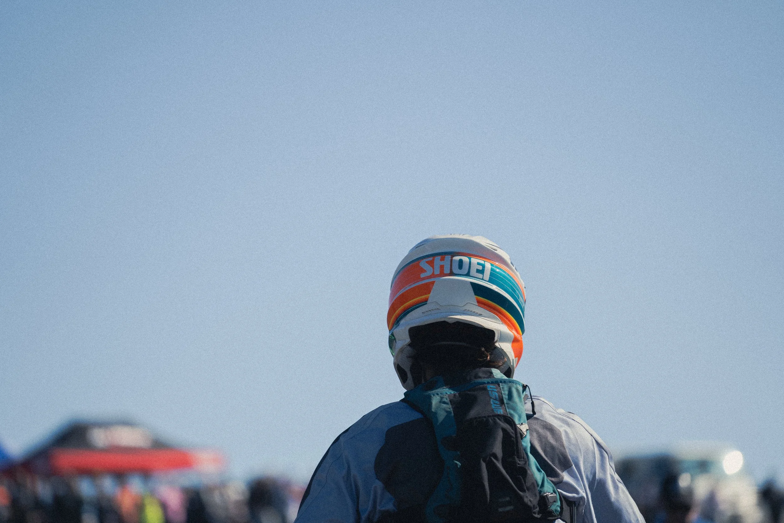 A person standing outdoors wearing a helmet and backpack with a clear sky in the background.