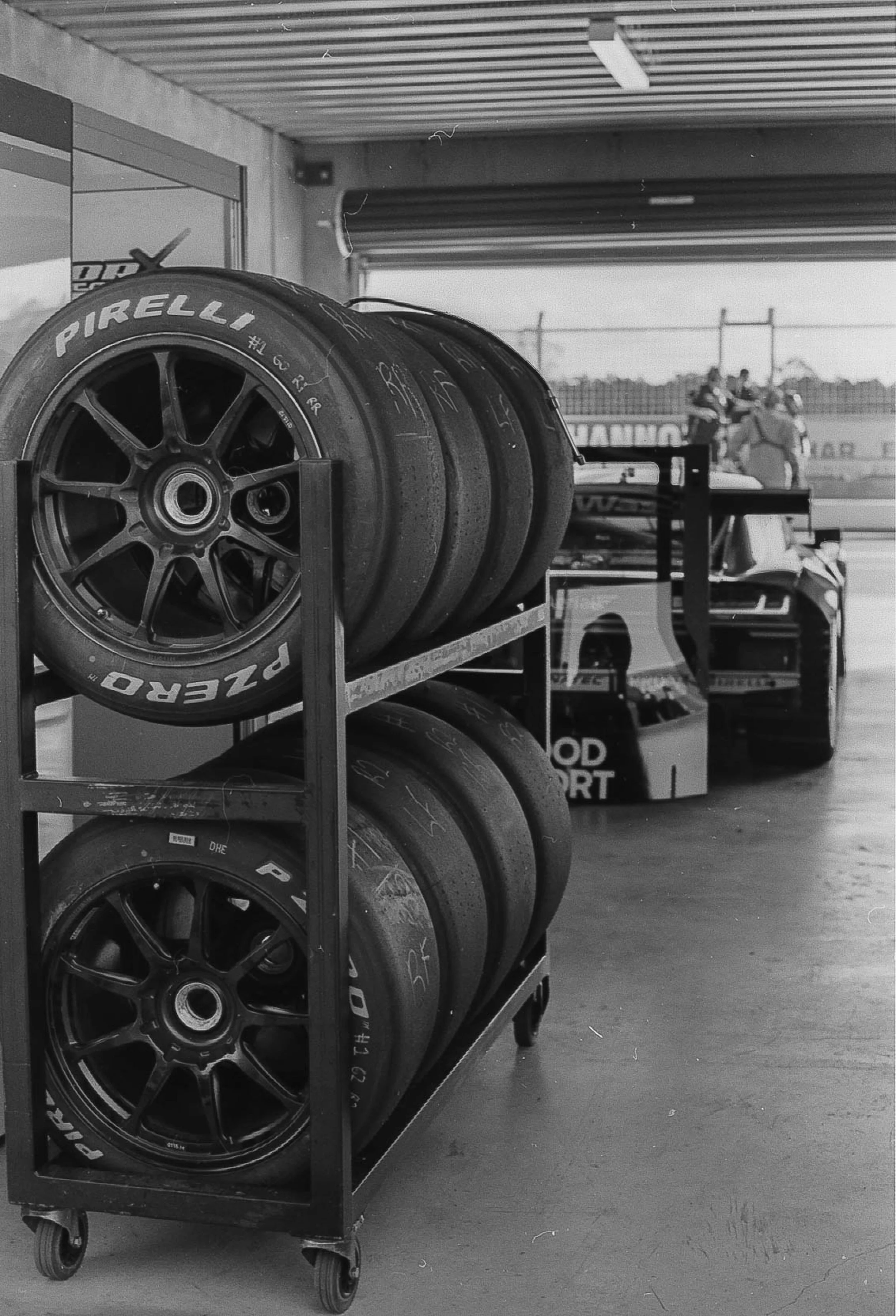 Race car wheels and tires on a metal cart in a garage at a race track.