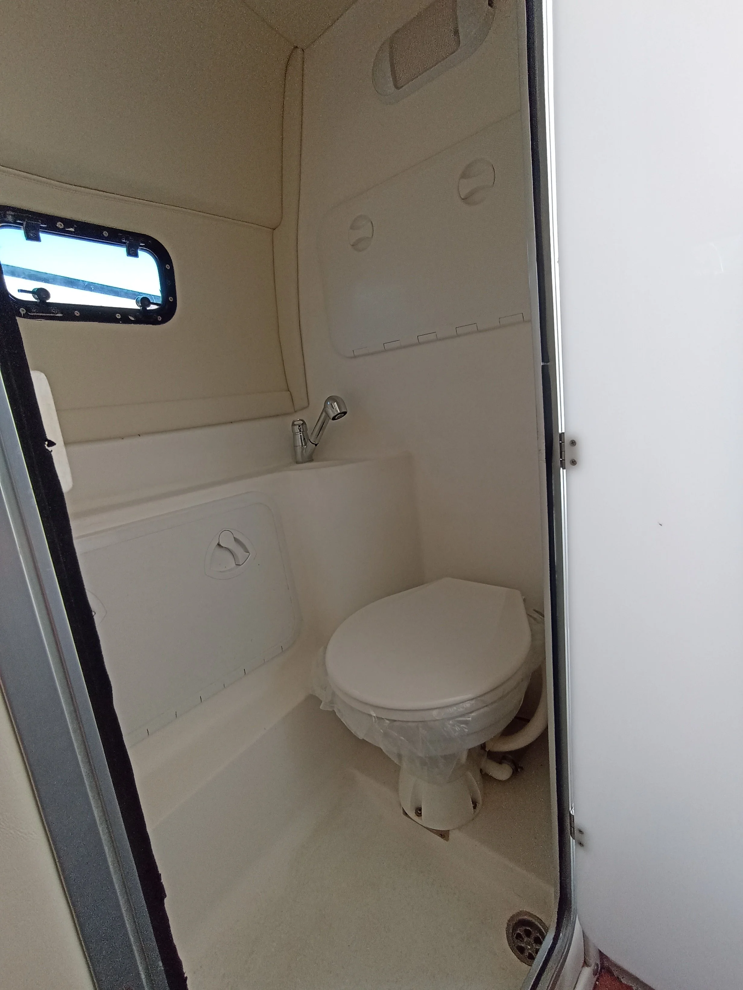 Small bathroom with a toilet, a small sink, a window, and a door.