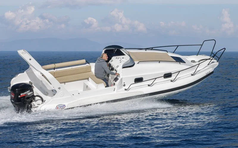 A person operating a white motorboat on the ocean with beige seating and a black canopy, with a Suzuki outboard motor at the stern.