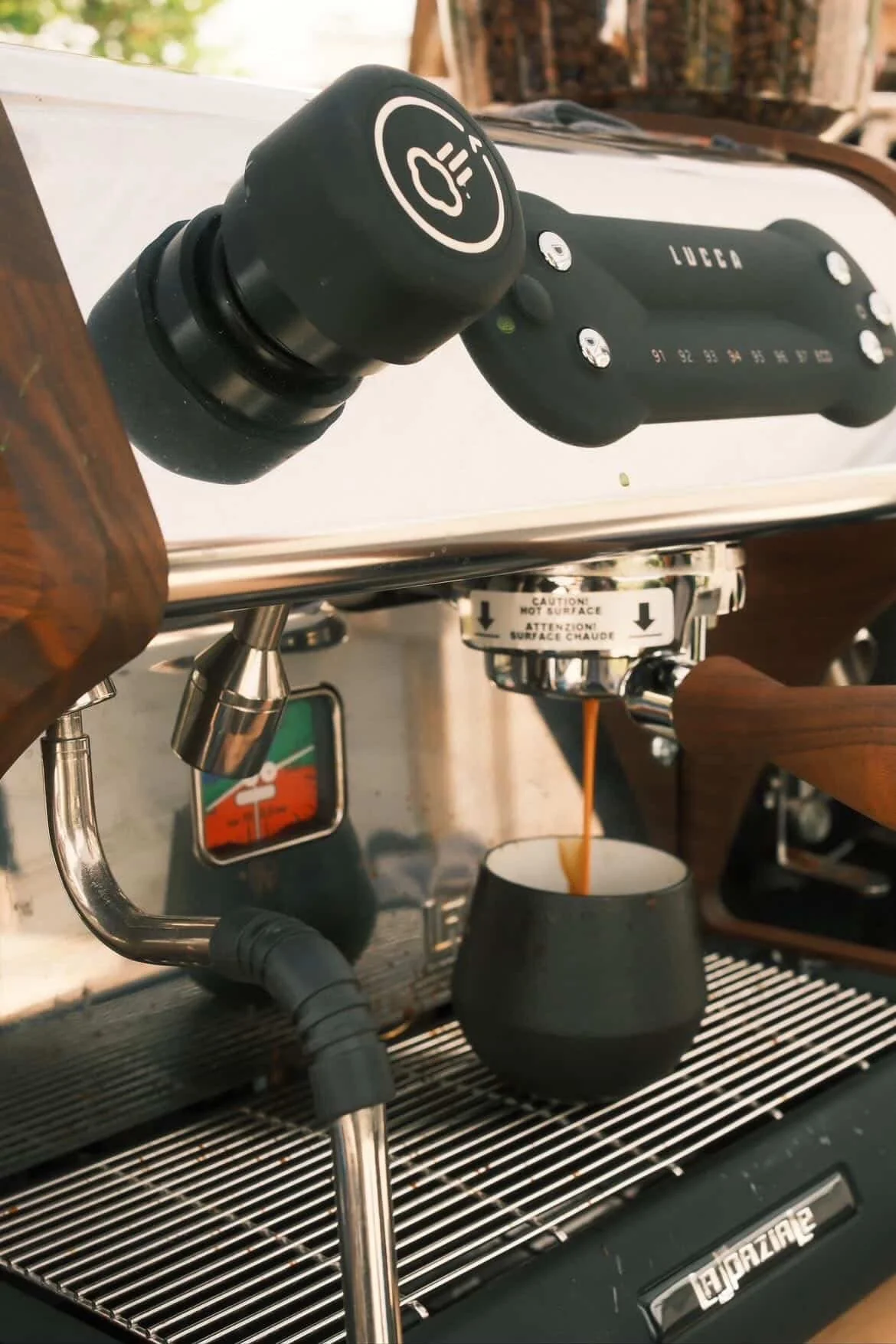 Close-up of a La Marzocco espresso machine pouring coffee into a cup with a black mug underneath.