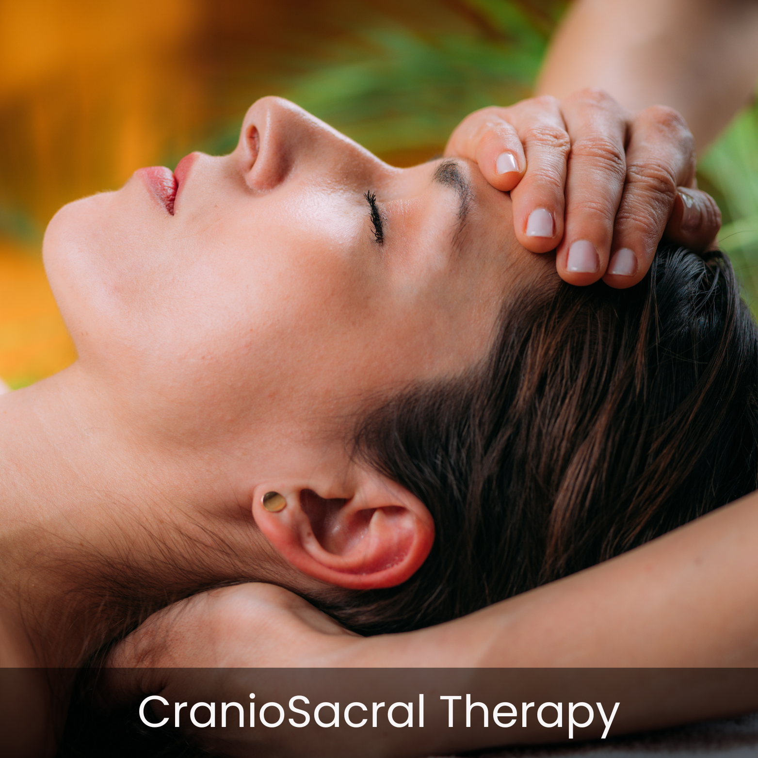 A woman lying down receiving craniosacral therapy, a gentle touch therapy on her forehead, with a colorful, blurred background.