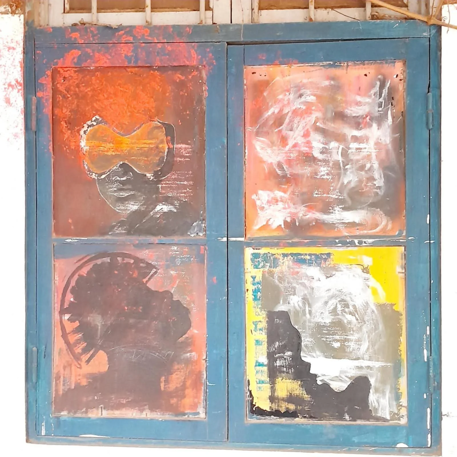 Four painted squares on a blue wooden frame, featuring abstract, silhouette, and portrait-style artwork in various colors and styles.