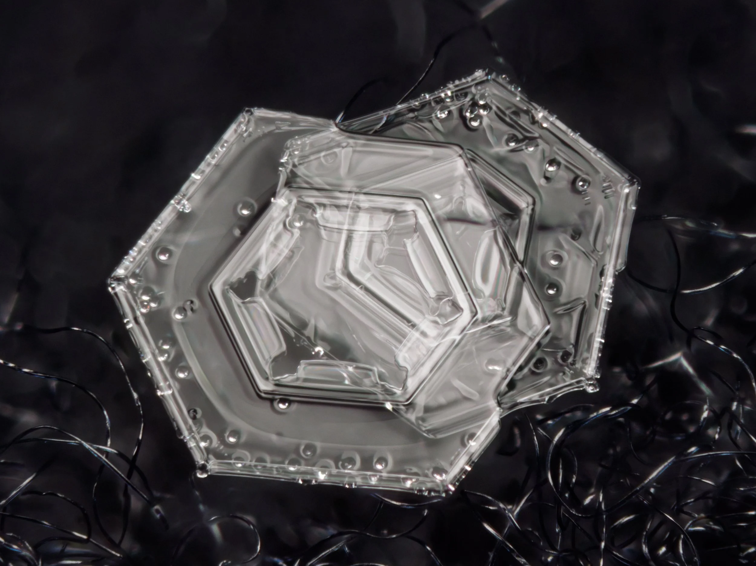 A macro photograph of two snow crystals attached to each other, with frozen air bubbles clearly visible.