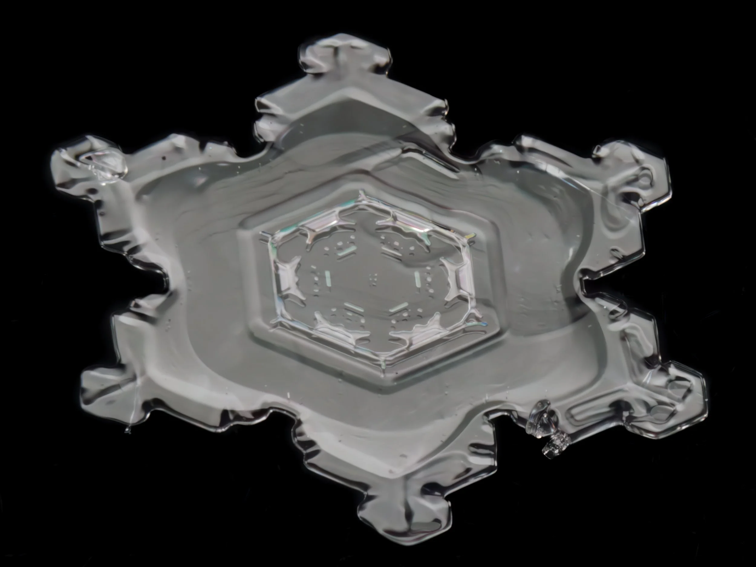 Macro photograph of a clear, cup-shaped snowflake.