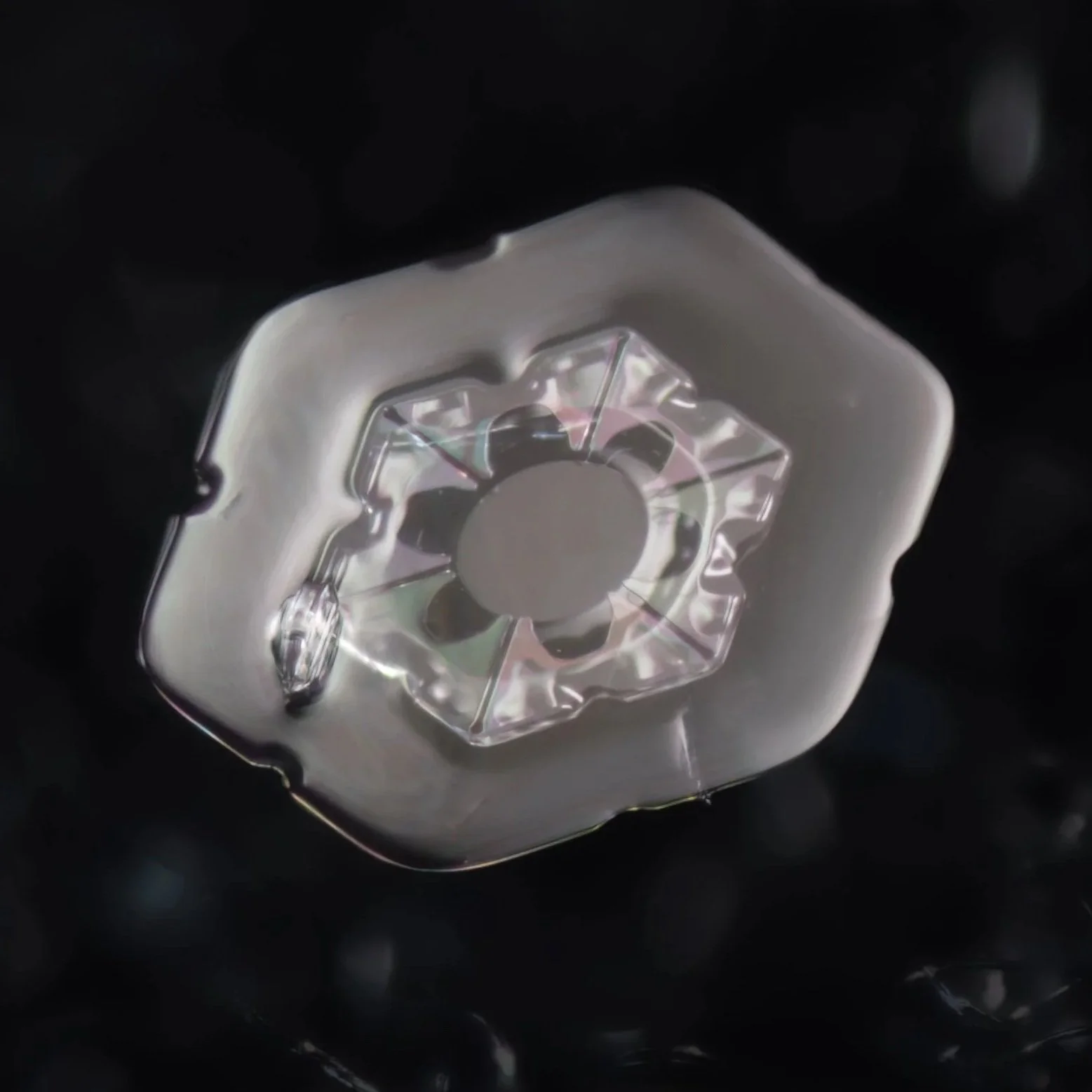 Macro photograph of a hexagonal colorful snow crystal.