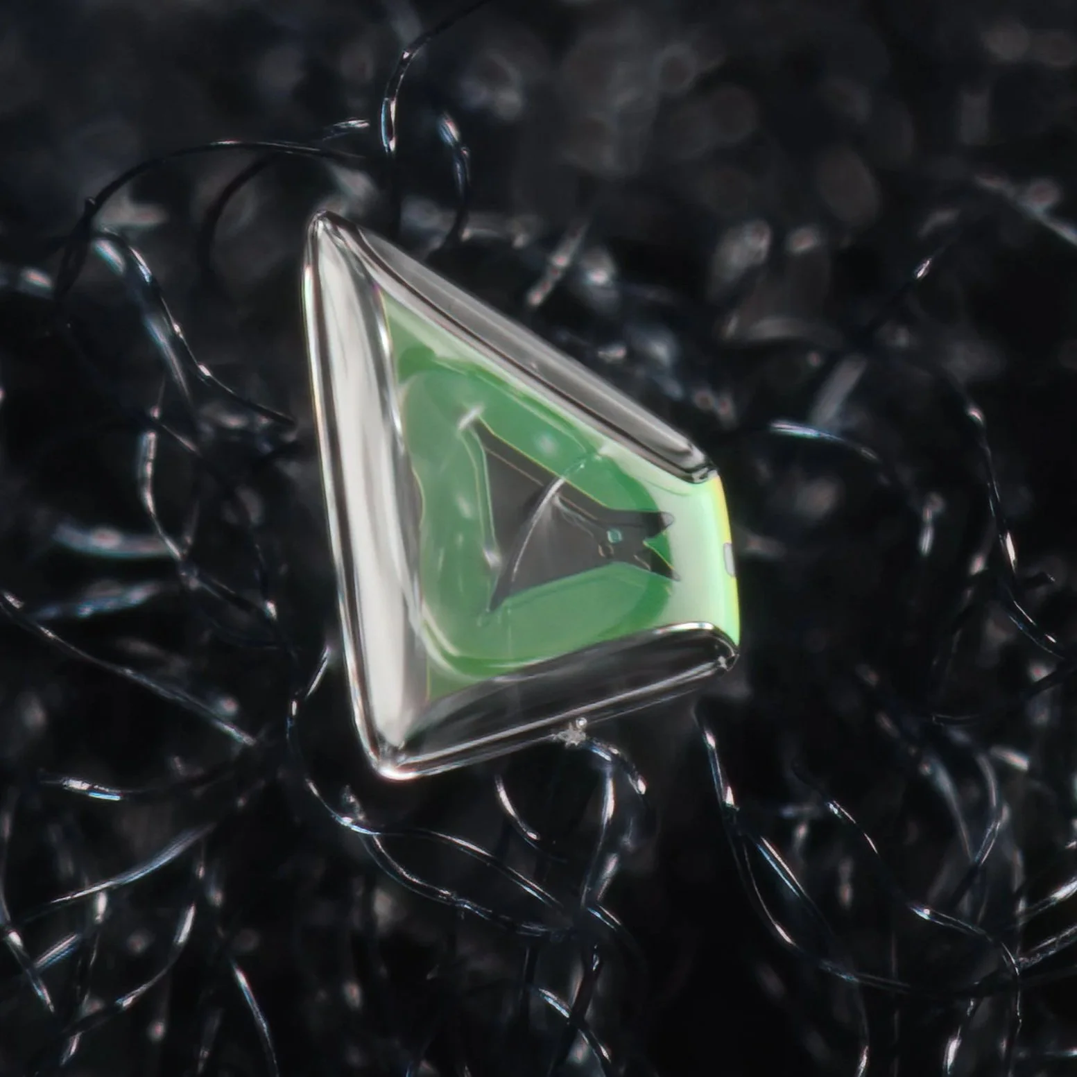 Macro photograph of a small, colorful triangular snow crystal.