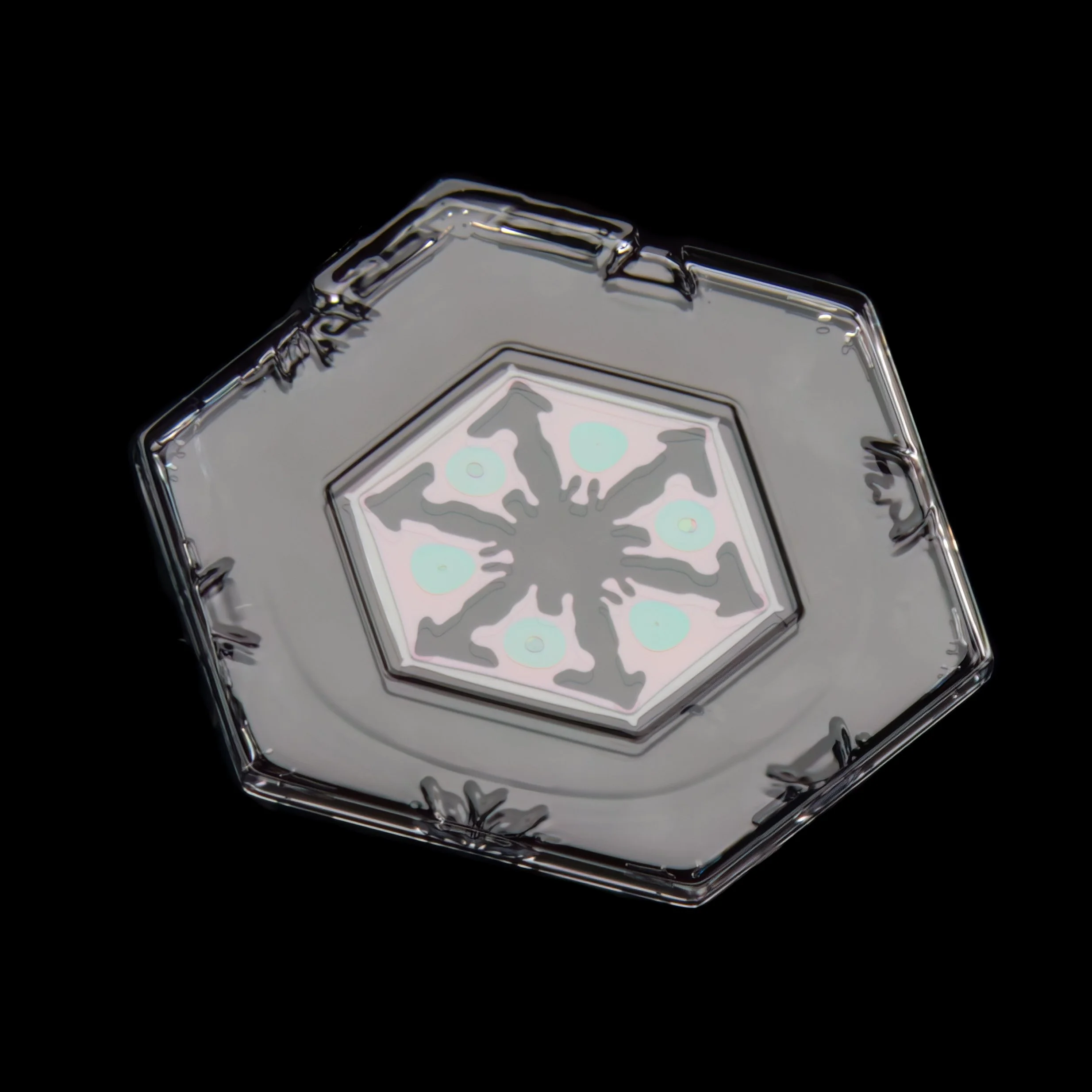 Macro photograph of a plate shaped snowflake with visible color refraction and intricate pattern captured in Oulu, Finland.