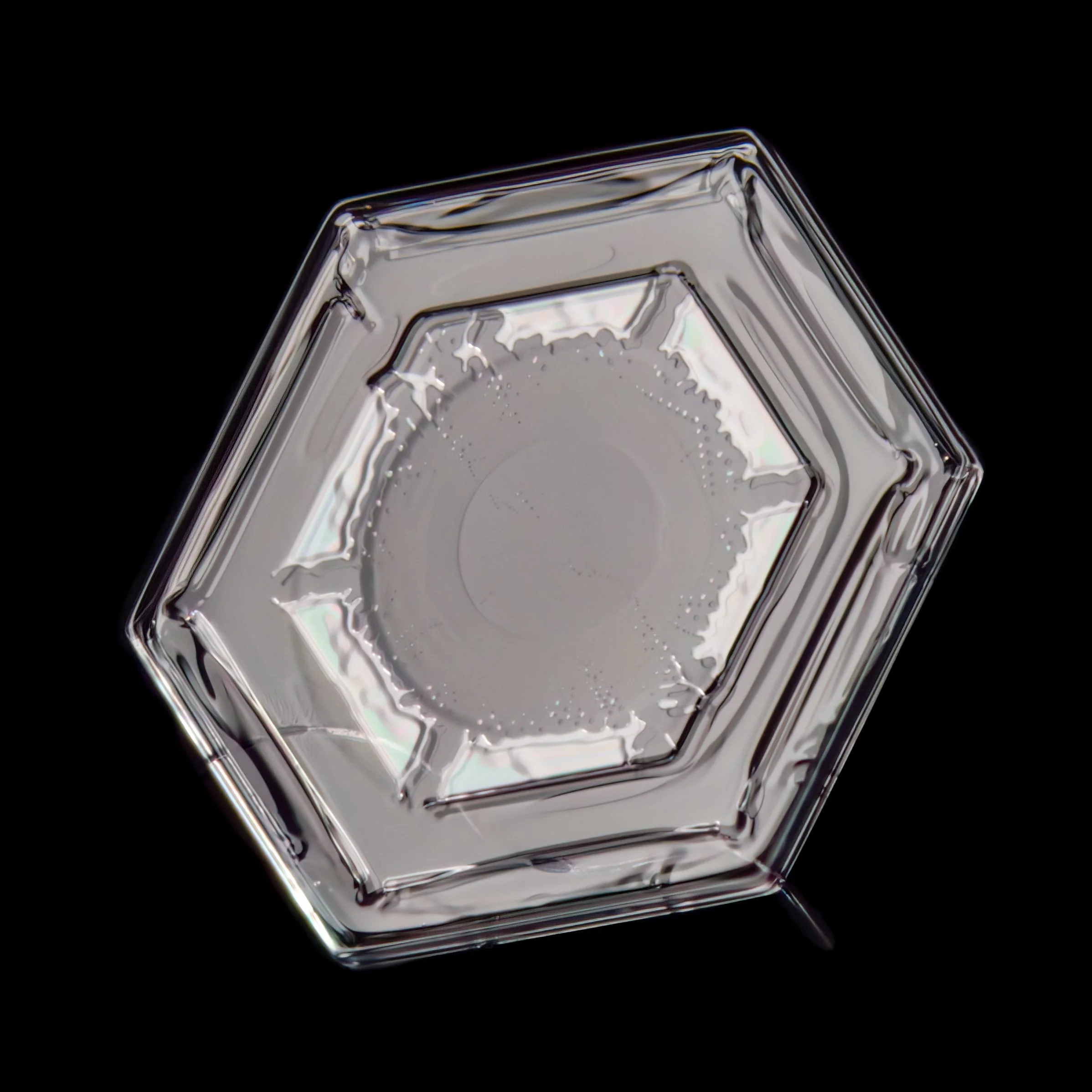 Macro photograph of a small plate snow crystal with visible color refraction.