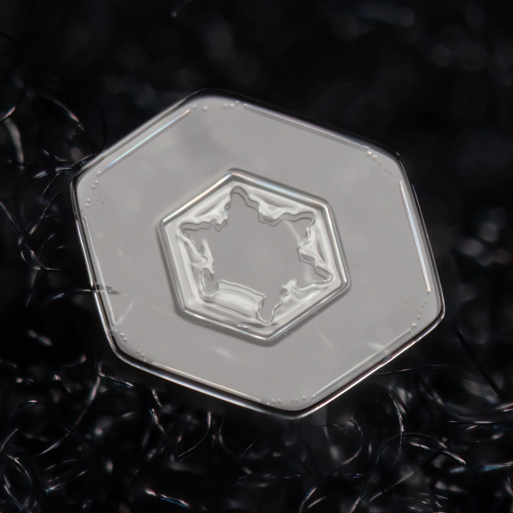 Macro photograph of a clear simple plate snowflake with a star like pattern in the center part.