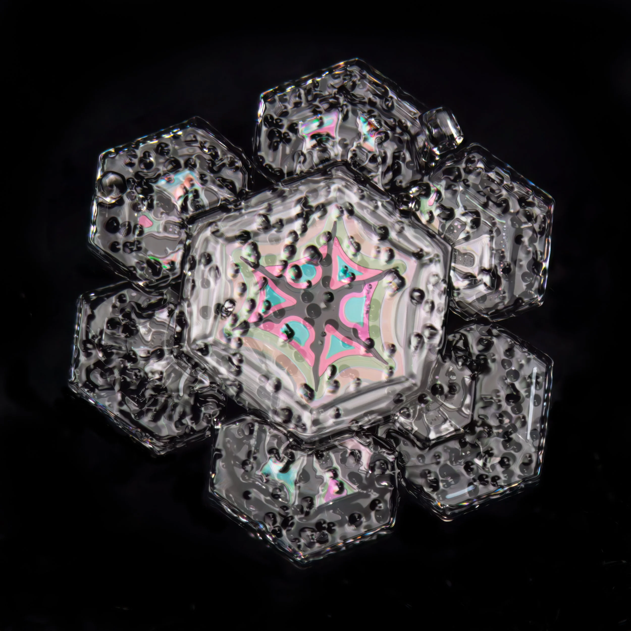 Macro photograph of a sectored plate snow crystal with a decorative pink, blue, and green snowflake pattern inside.