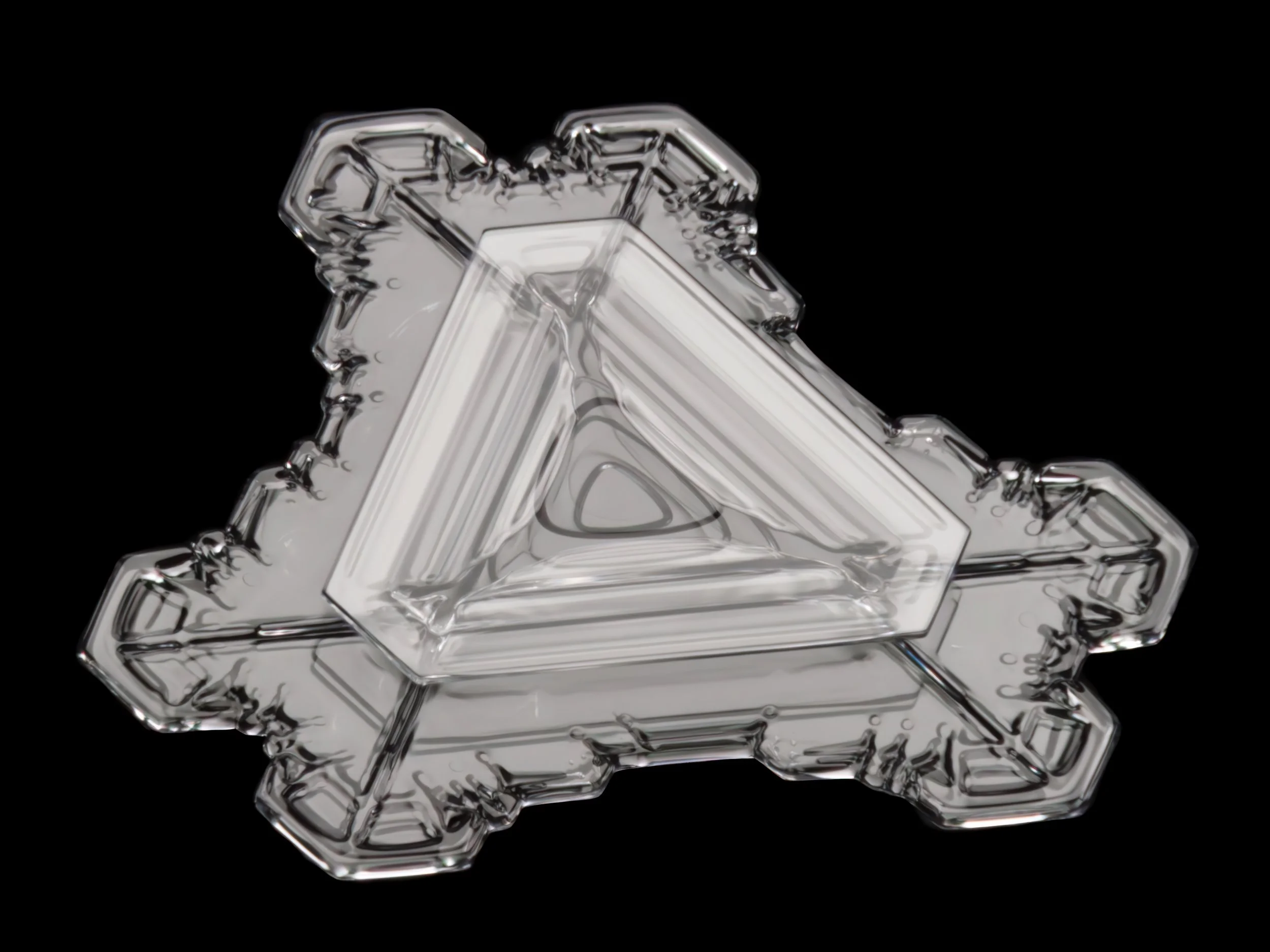 Macro photograph of a triangular double plate snow crystal with sharp edges.