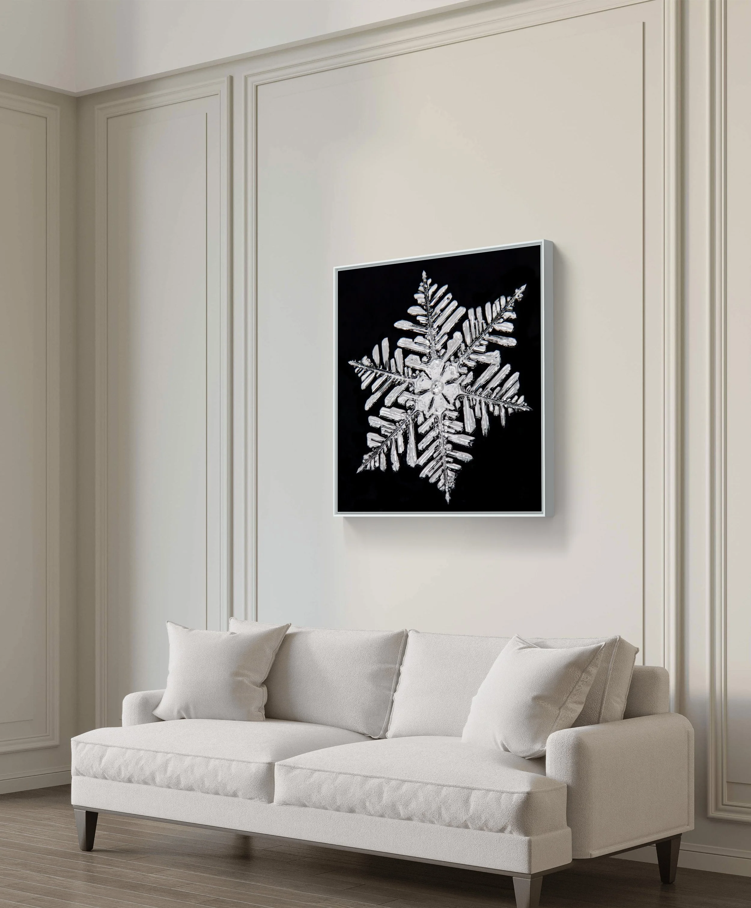 A framed black and white photo of a snowflake hangs on a white wall in a living room.