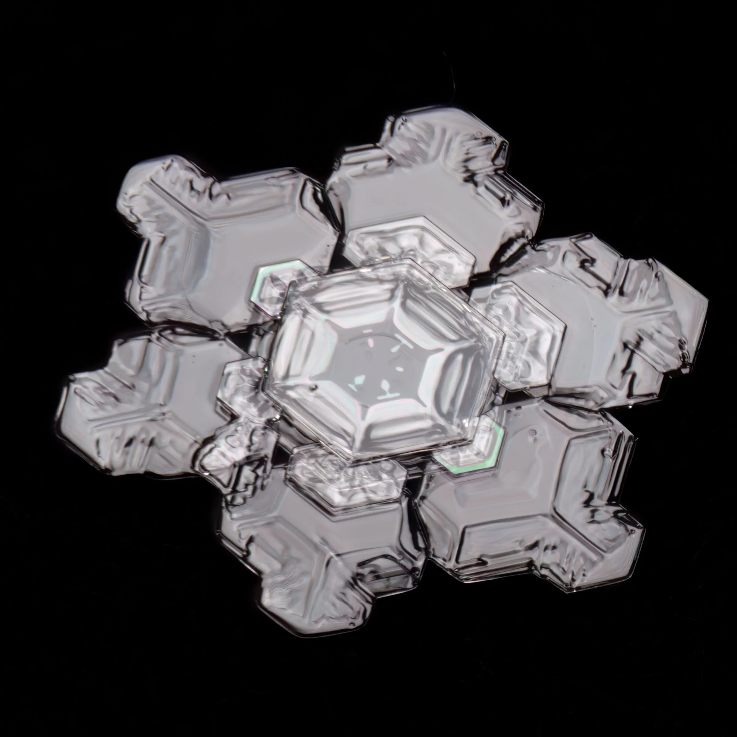 Macro photograph of a large, clear, geometric snowflake.