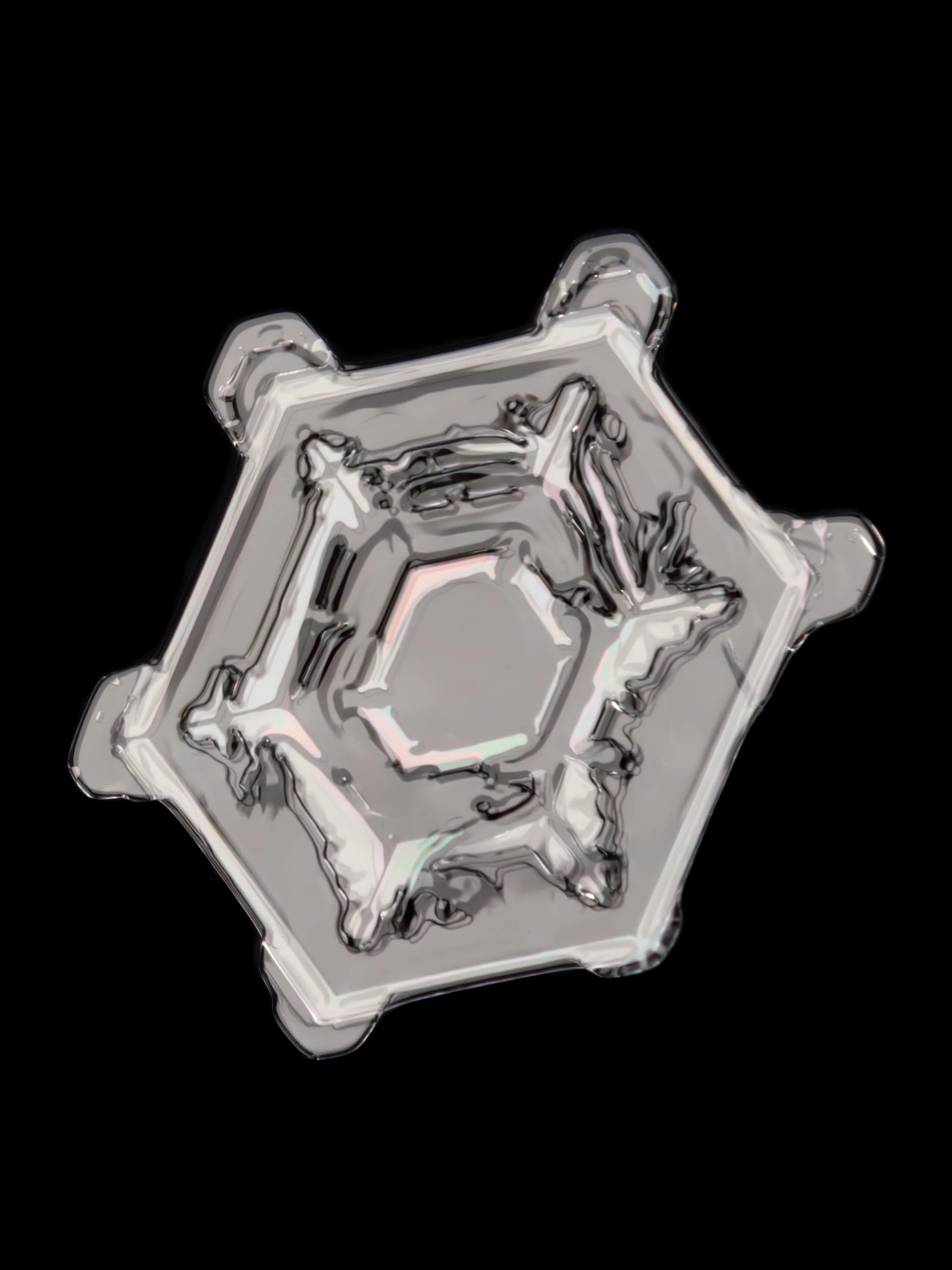 Macro photograph of a sectored plate snowflake with a colourful hexagonal pattern in the center.