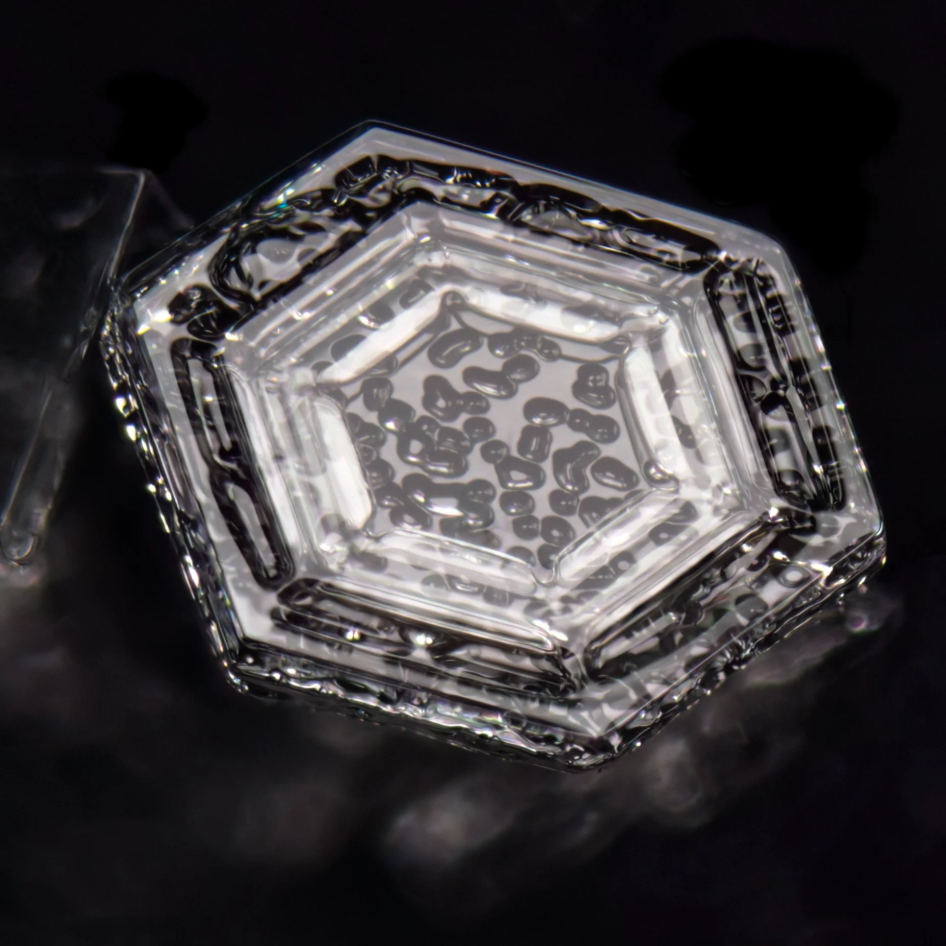 Macro photograph of a snow crystal with visible water droplets on its surface.
