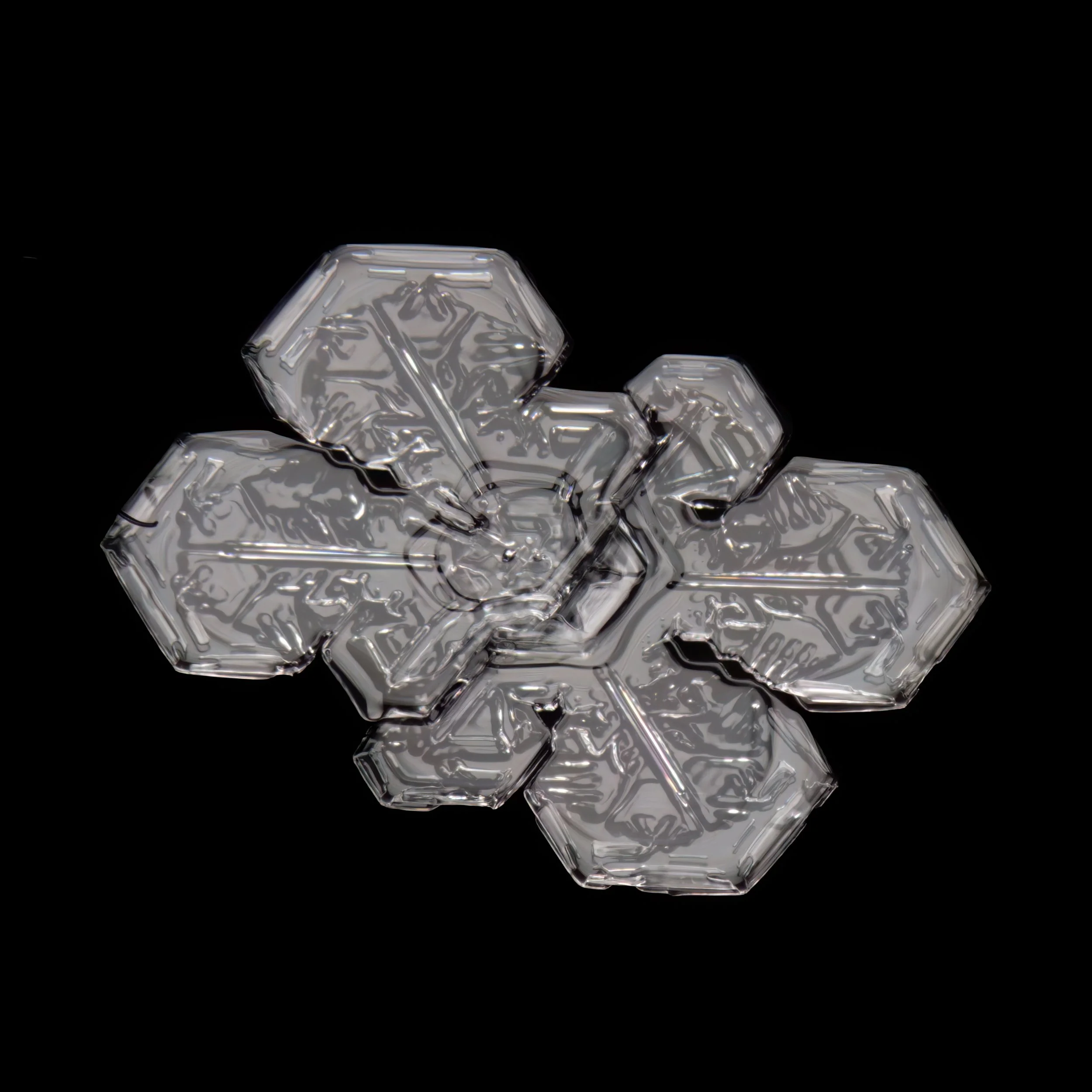 Macro photograph of a clear, irregular shaped snowflake with intricate patterns.