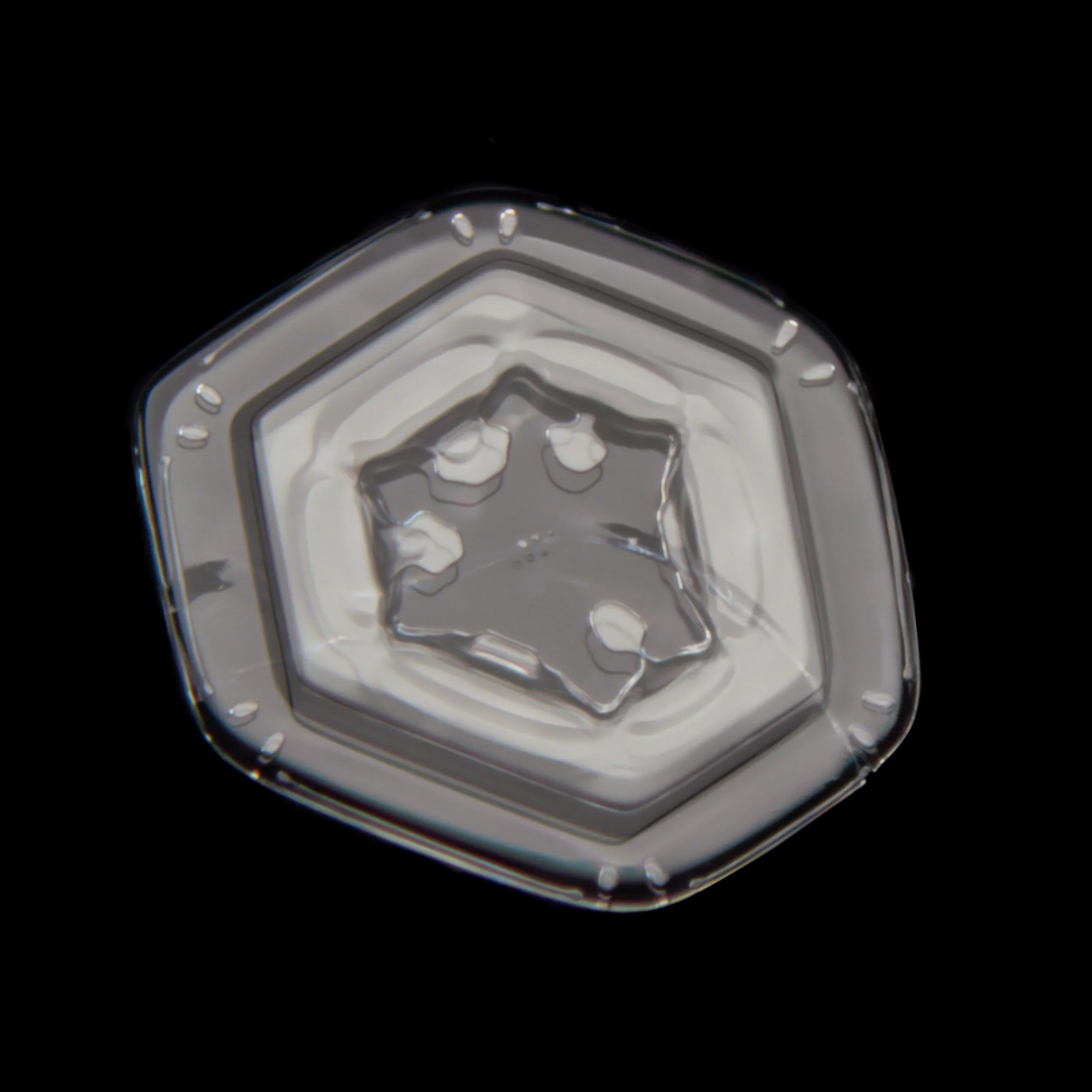 Macro photograph of a small plate snow crystal with an irregular center pattern.
