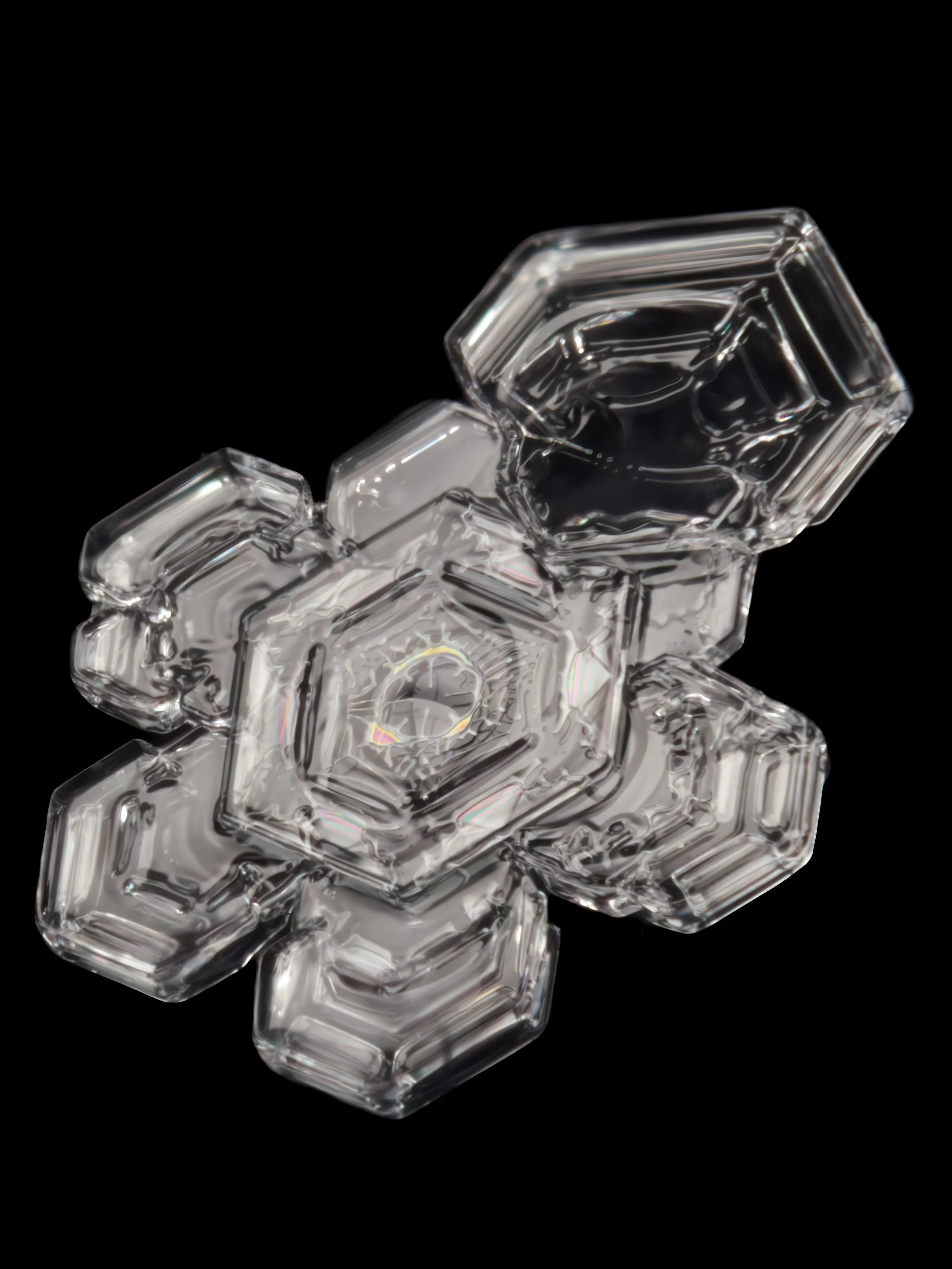 Macro photograph of a clear glassy sectored plate snowflake with colorful patterns.