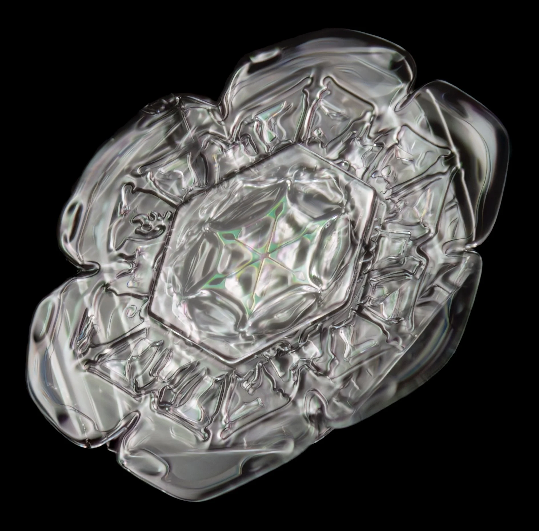 Macro photograph of a sectored plate snowflake with a colourful center pattern.