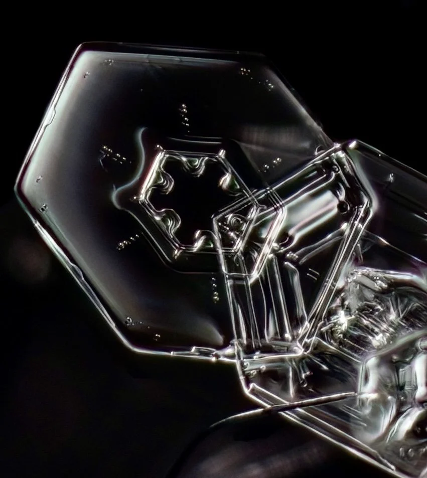 Macro photograph of a clear simple plate snowflake with an intricate pattern in the center part.