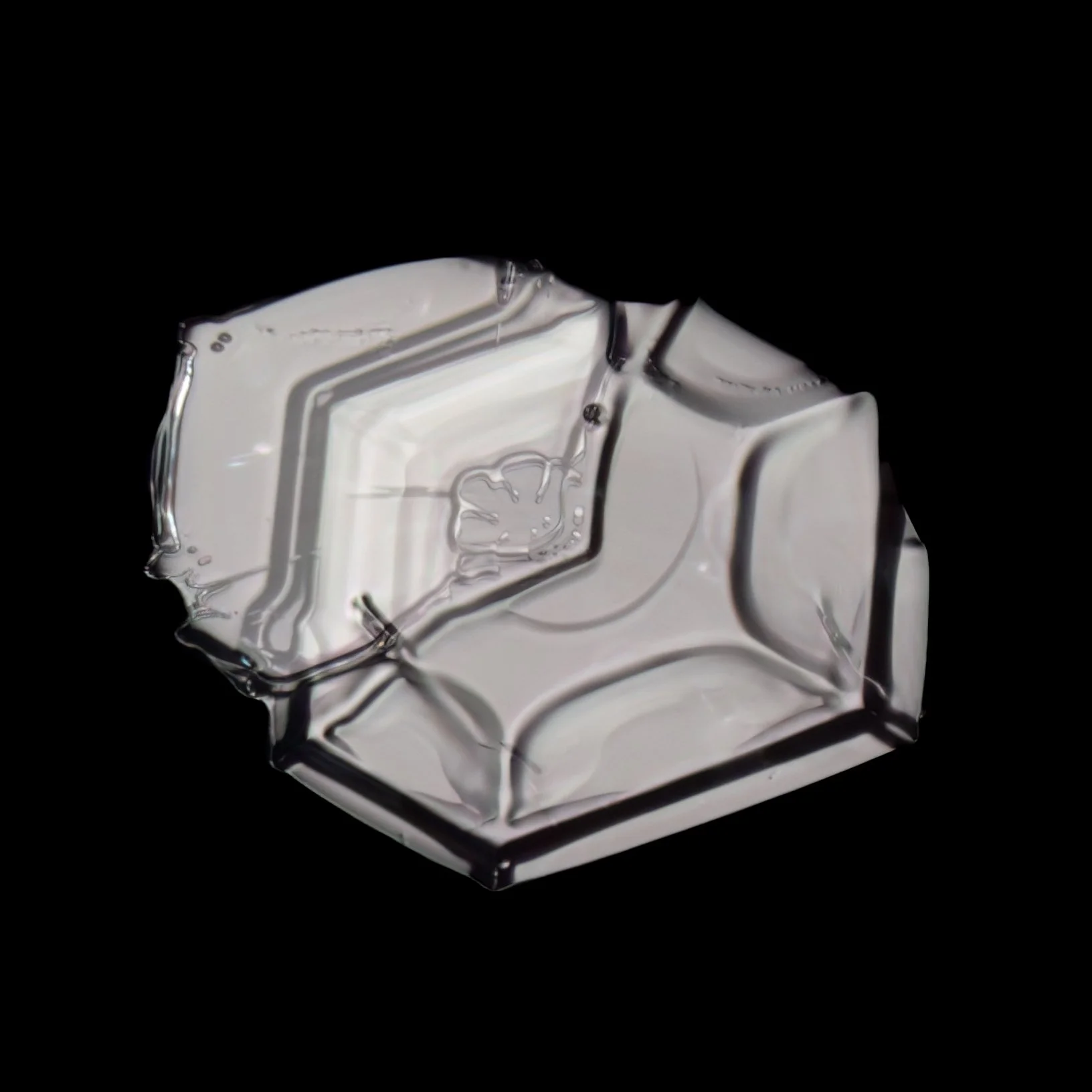 Macro photograph of a clear glassy irregular shaped snow crystal with a geometric design.