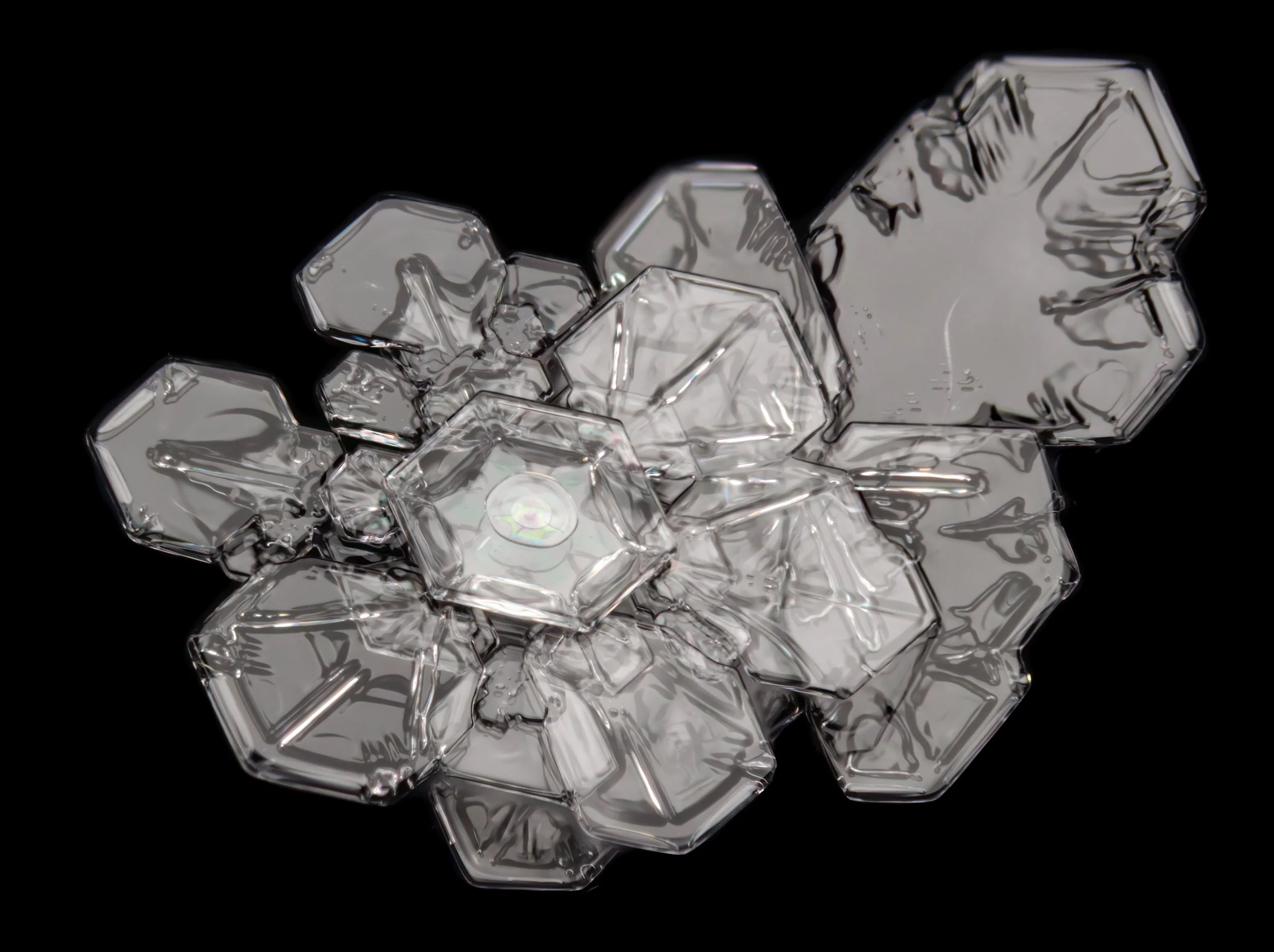 Macro photograph of a two irregular snow crystals with colourful center patterns from thin film interference.