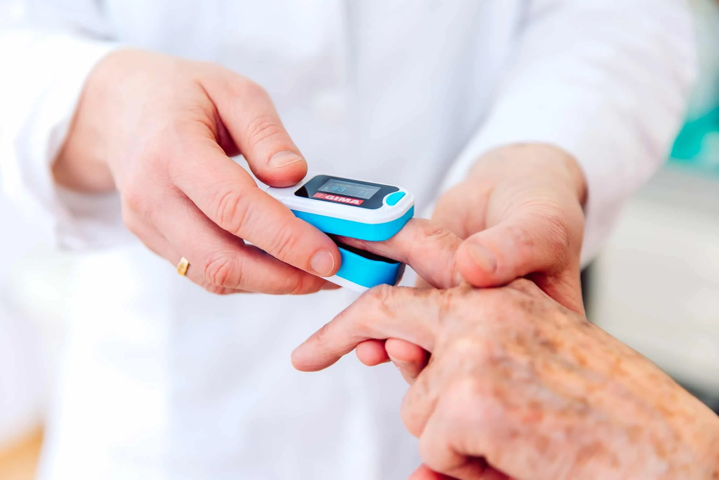 Arzt misst Blutzucker bei älterer Person mit Blutzuckermessgerät.