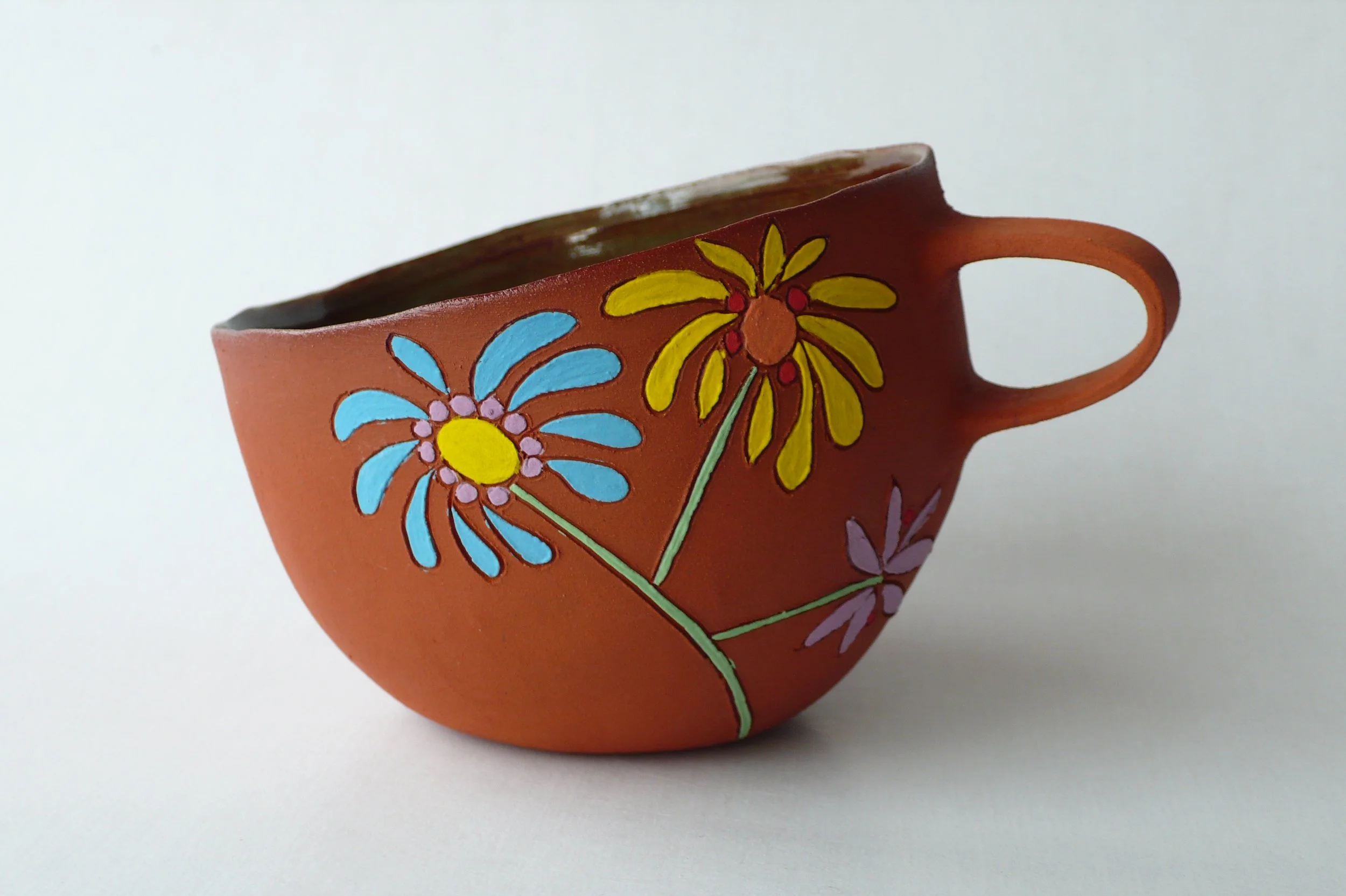 Hand-built red stoneware cup with floral inlaid patterns by Marisa Iona.