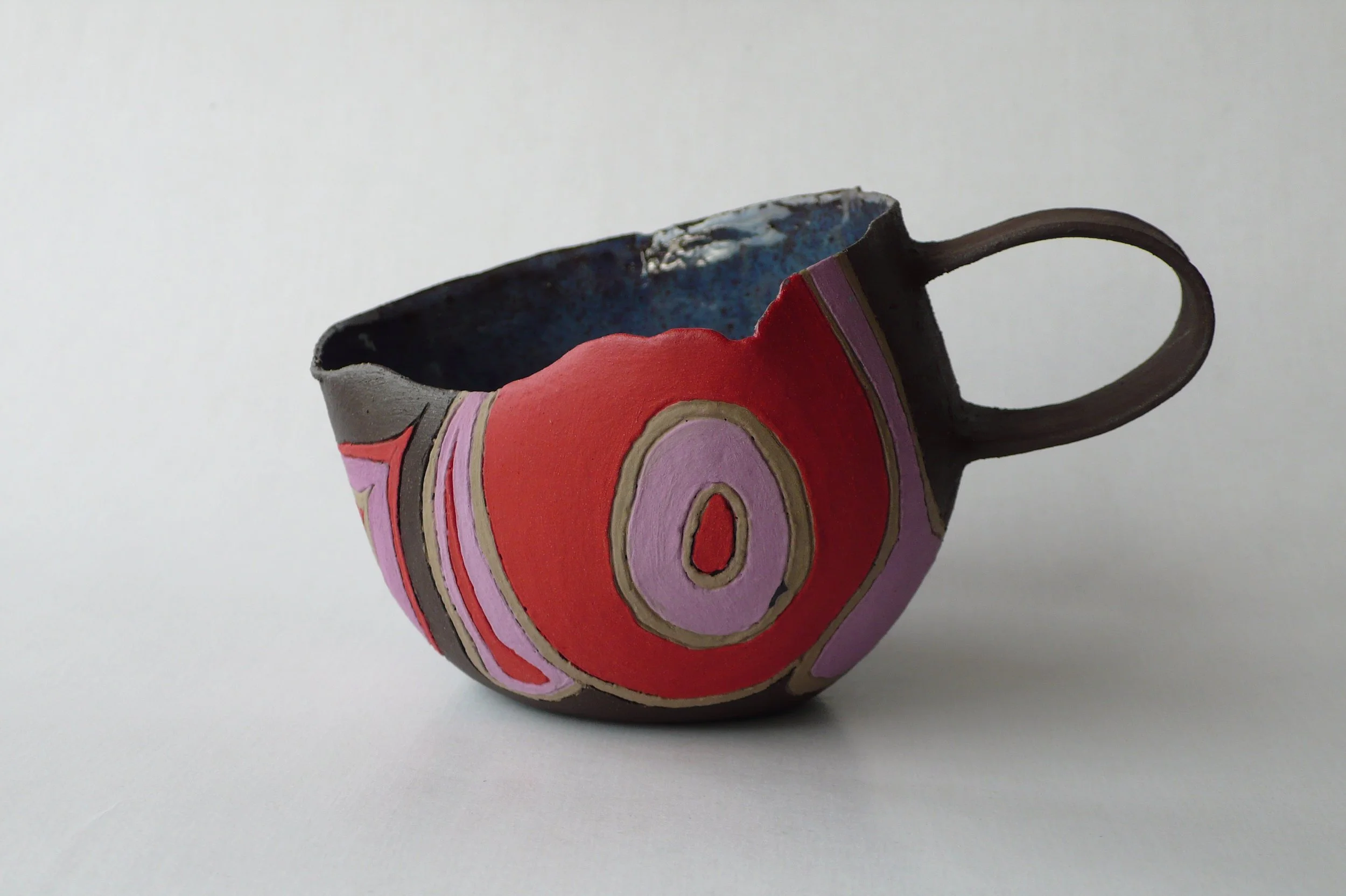Hand-built black stoneware cup with multi-colored rhythmic inlaid slips by Marisa Iona.