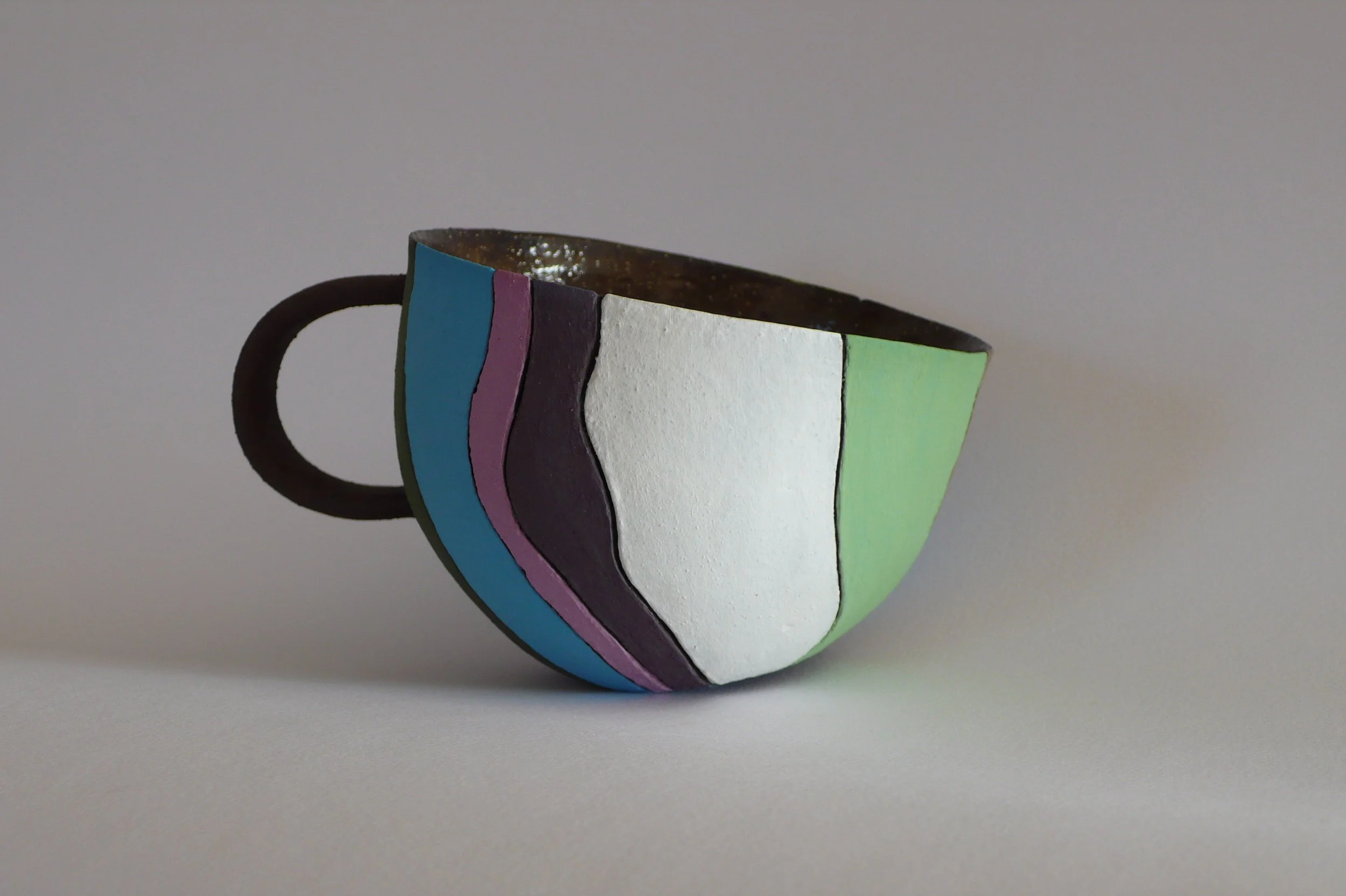 Contemporary hand-built black stoneware cup with vibrant multi-colored inlaid stripes by Marisa Iona.