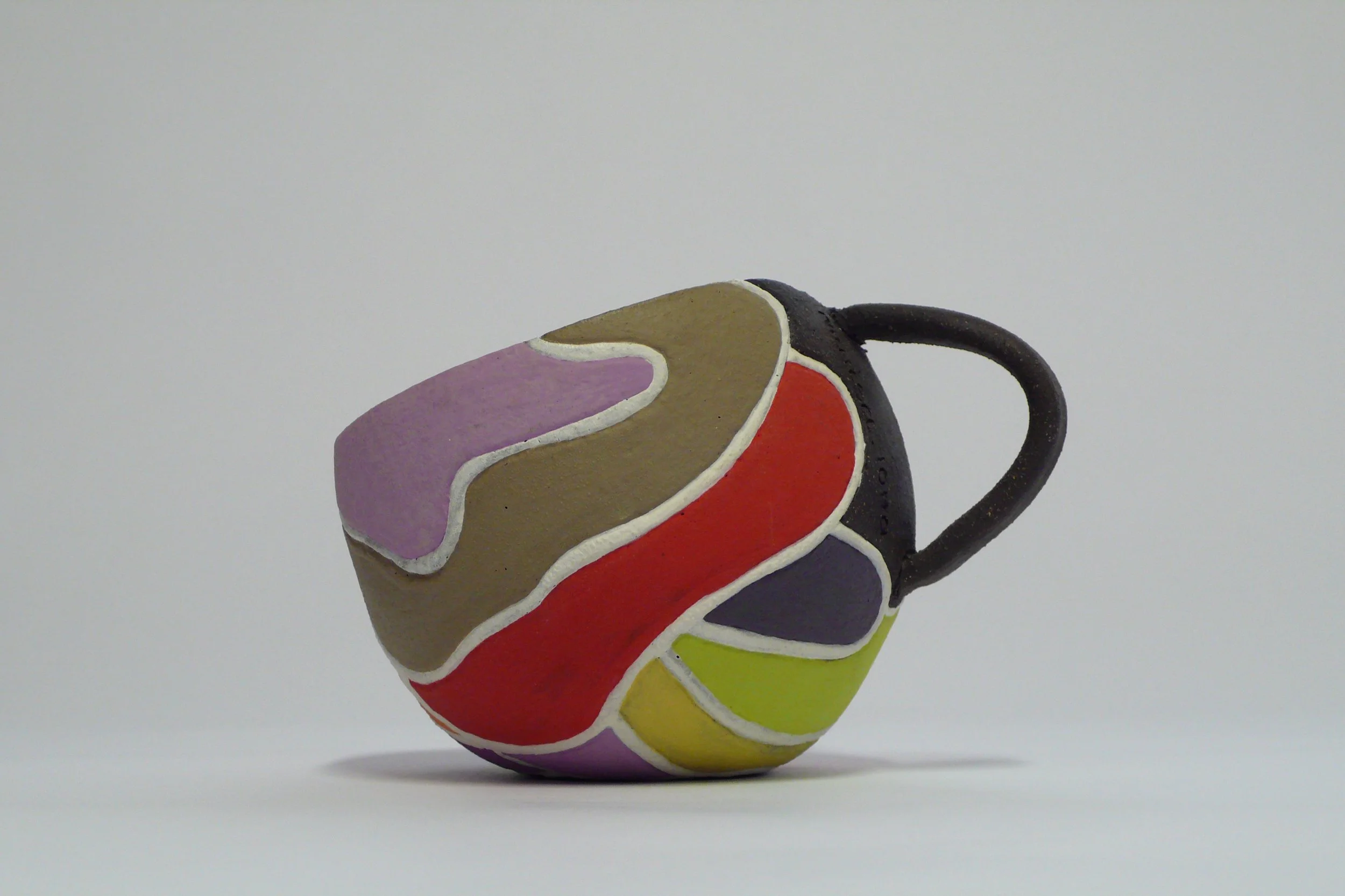 Hand-built black stoneware cup with multi-colored rhythmic inlaid slips by Marisa Iona.