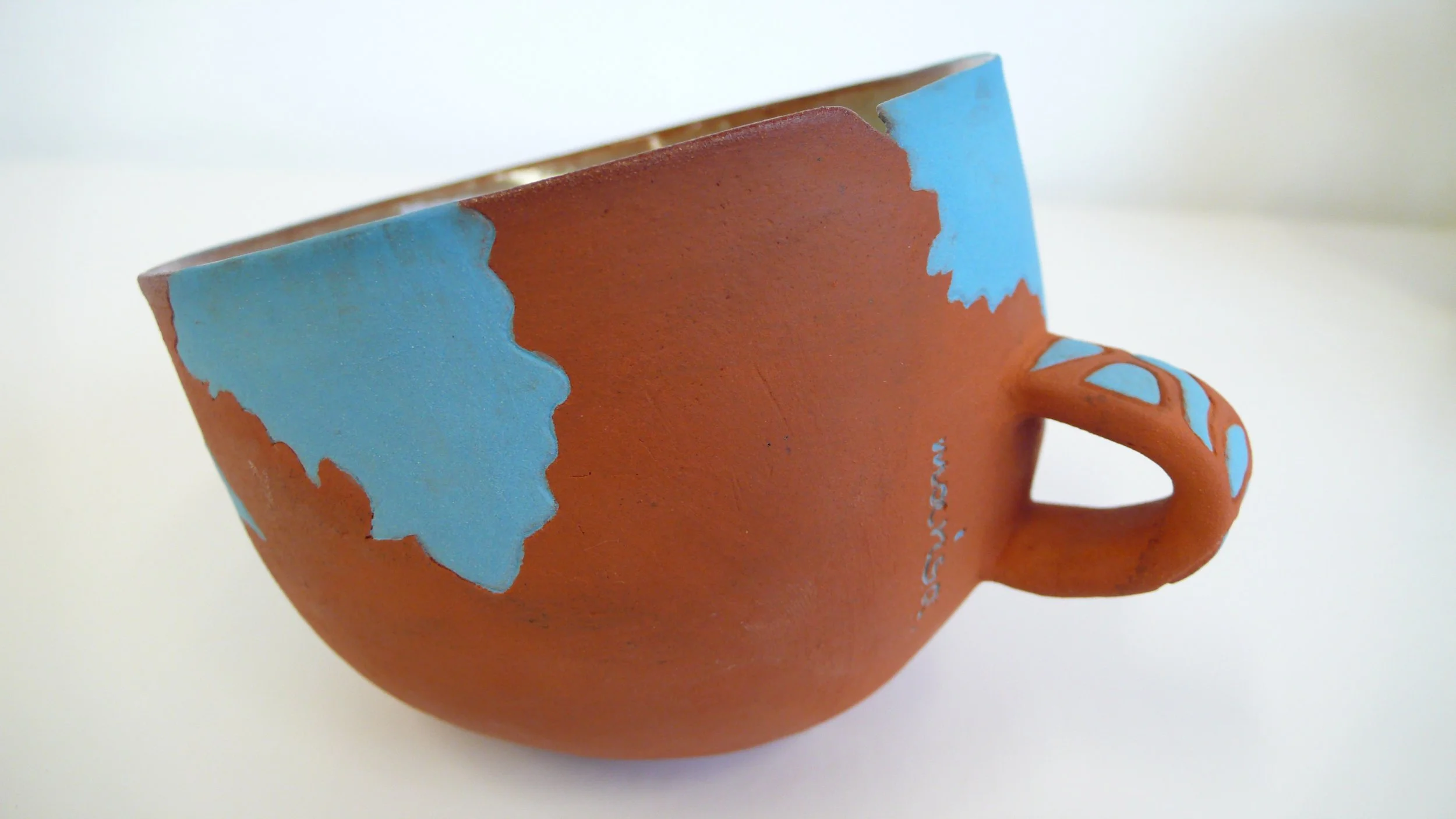 Hand-built red stoneware cup with blue cosmic inlaid patterns by Marisa Iona.