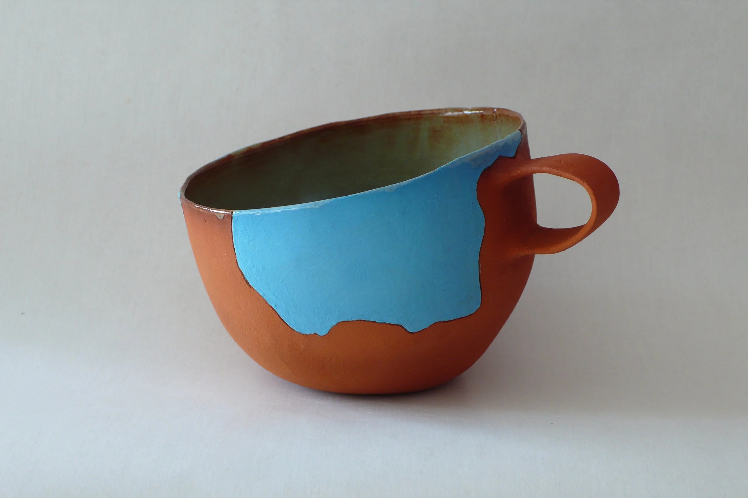 Hand-built red stoneware cup with blue cosmic inlaid patterns by Marisa Iona.